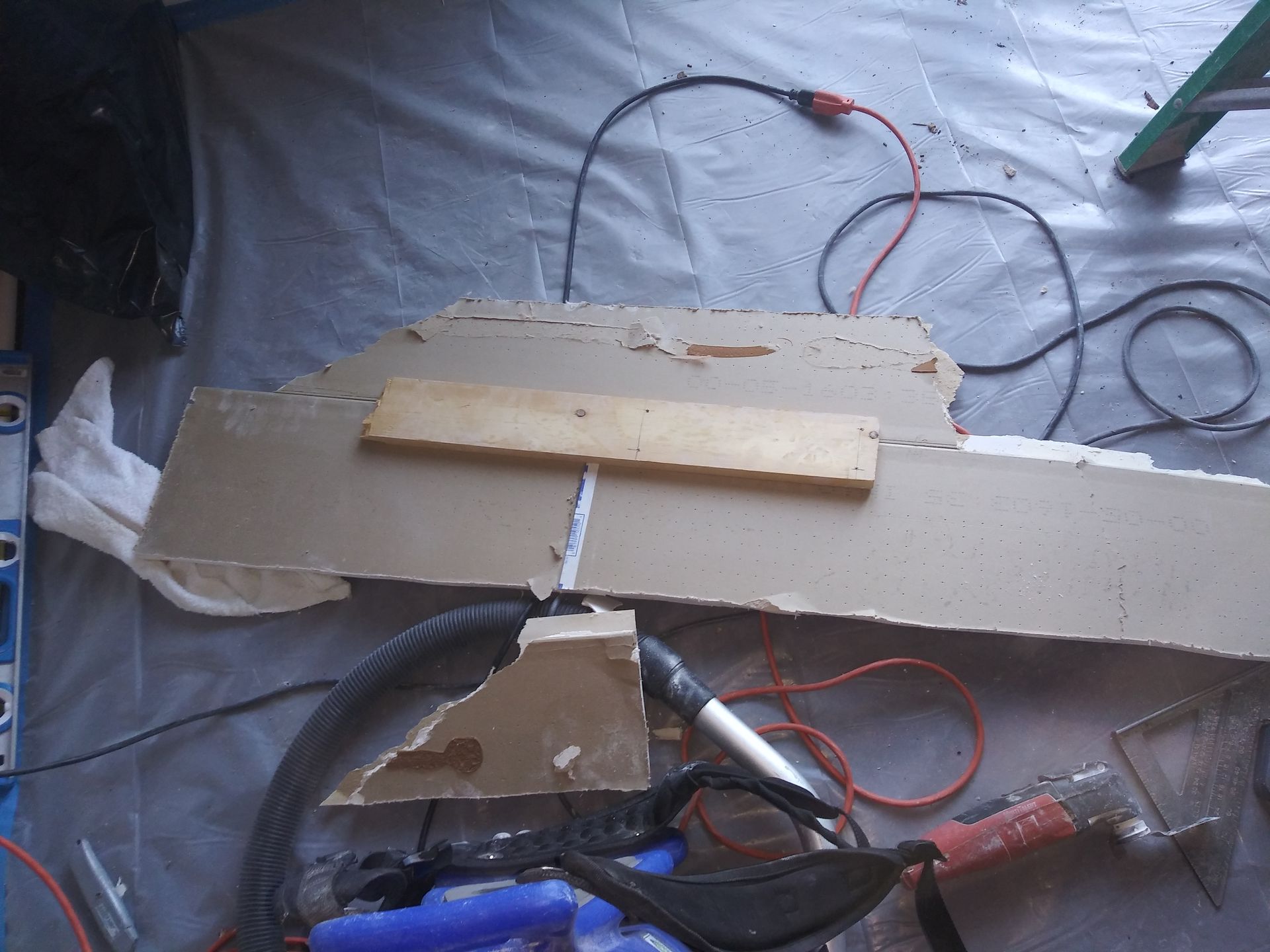 A piece of cardboard is sitting on the floor next to a drill and other tools