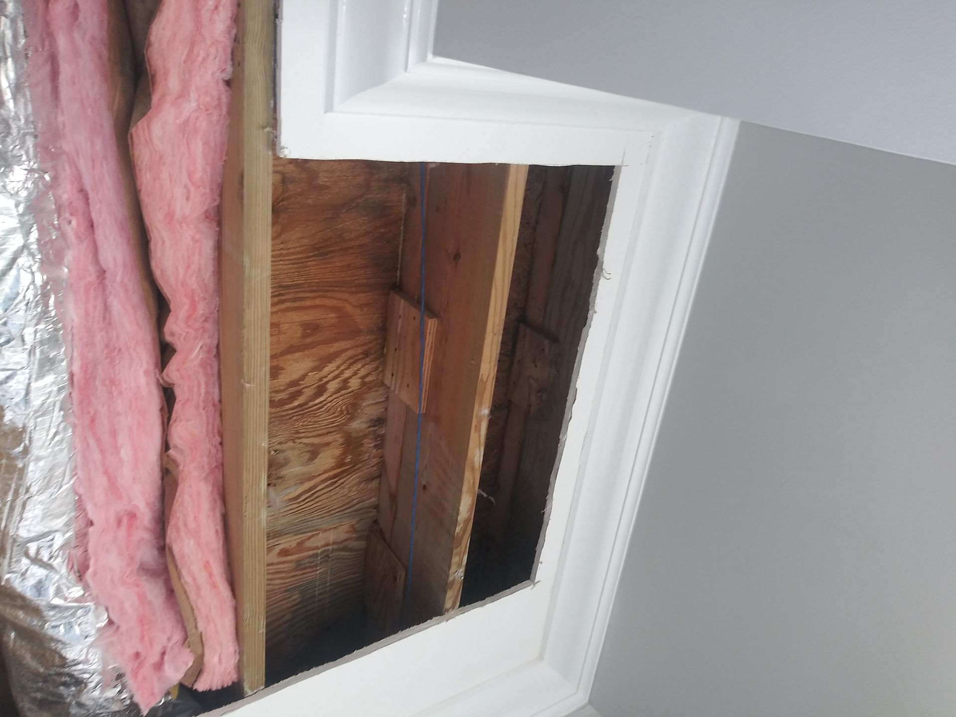 There is a hole in the wall with pink insulation.