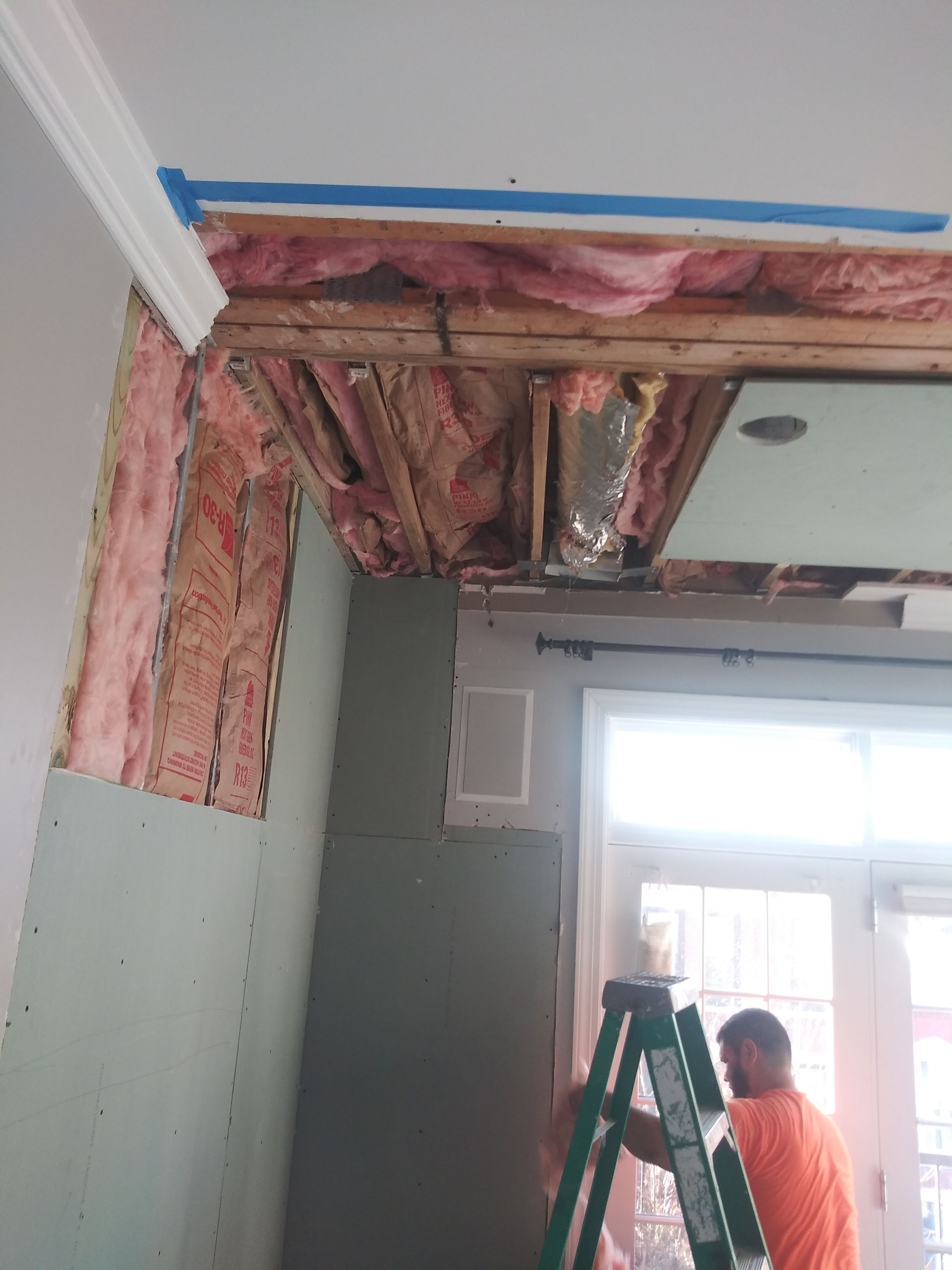 A man is standing on a ladder in a room.