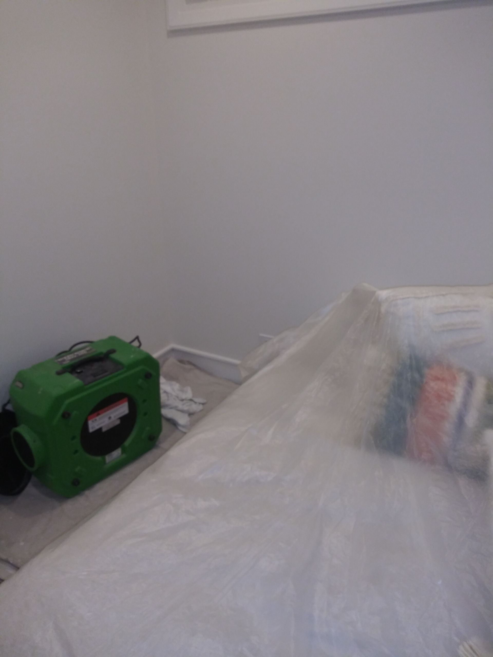 A green box is sitting on the floor next to a bed.