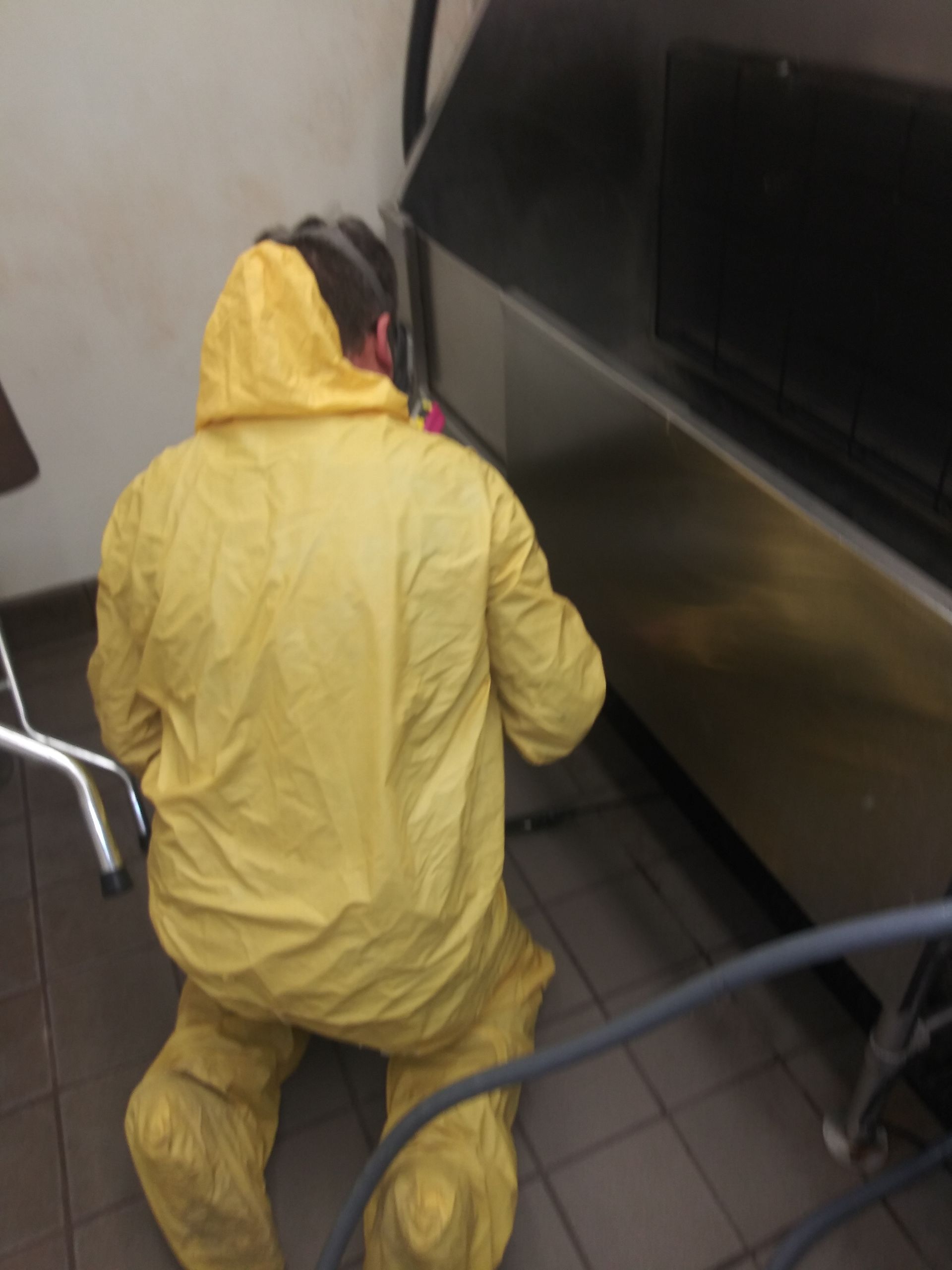 A man in a yellow suit is working on a machine