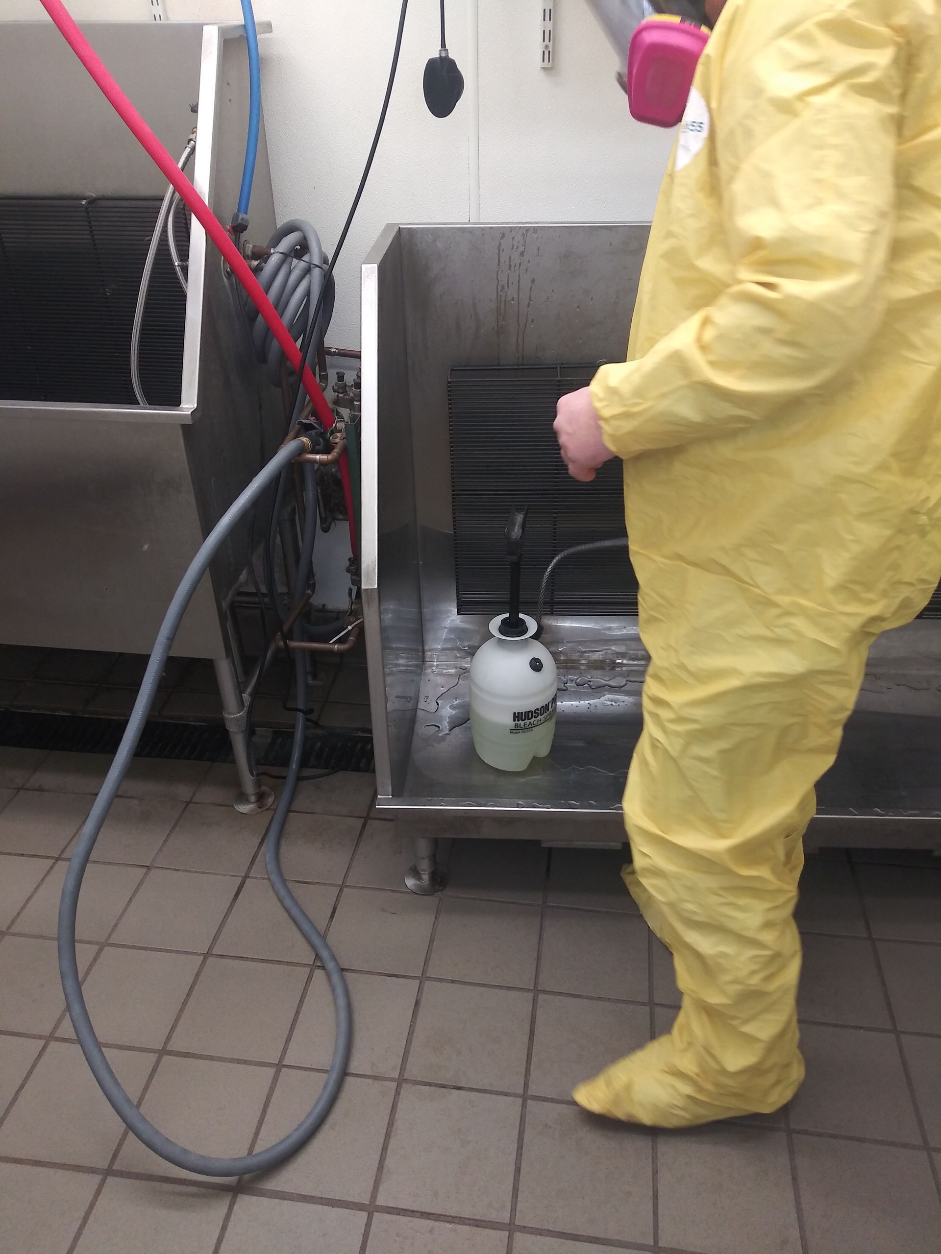 A man in a yellow suit is spraying something with a hose