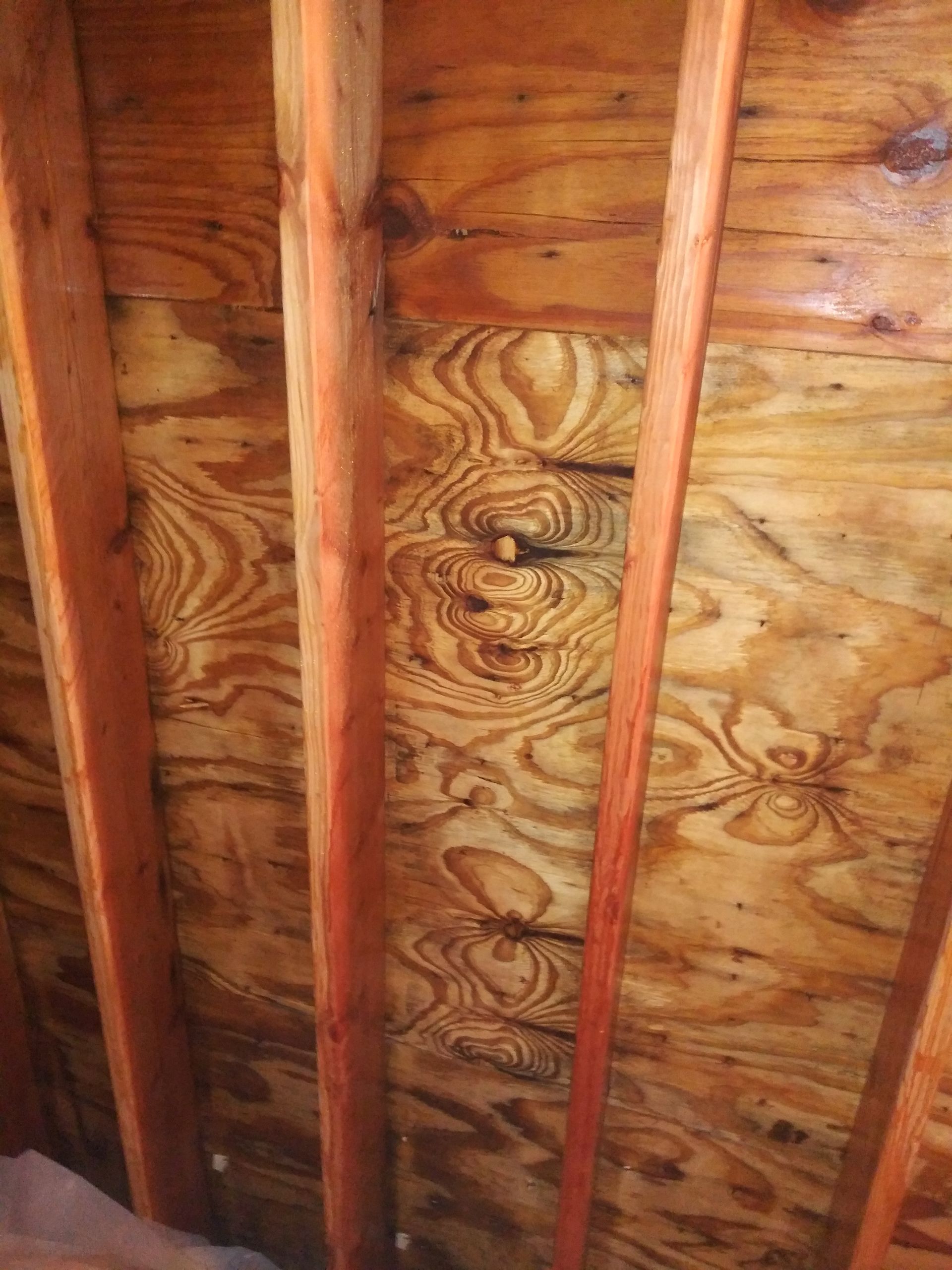 A close up of a wooden ceiling with a hole in it.