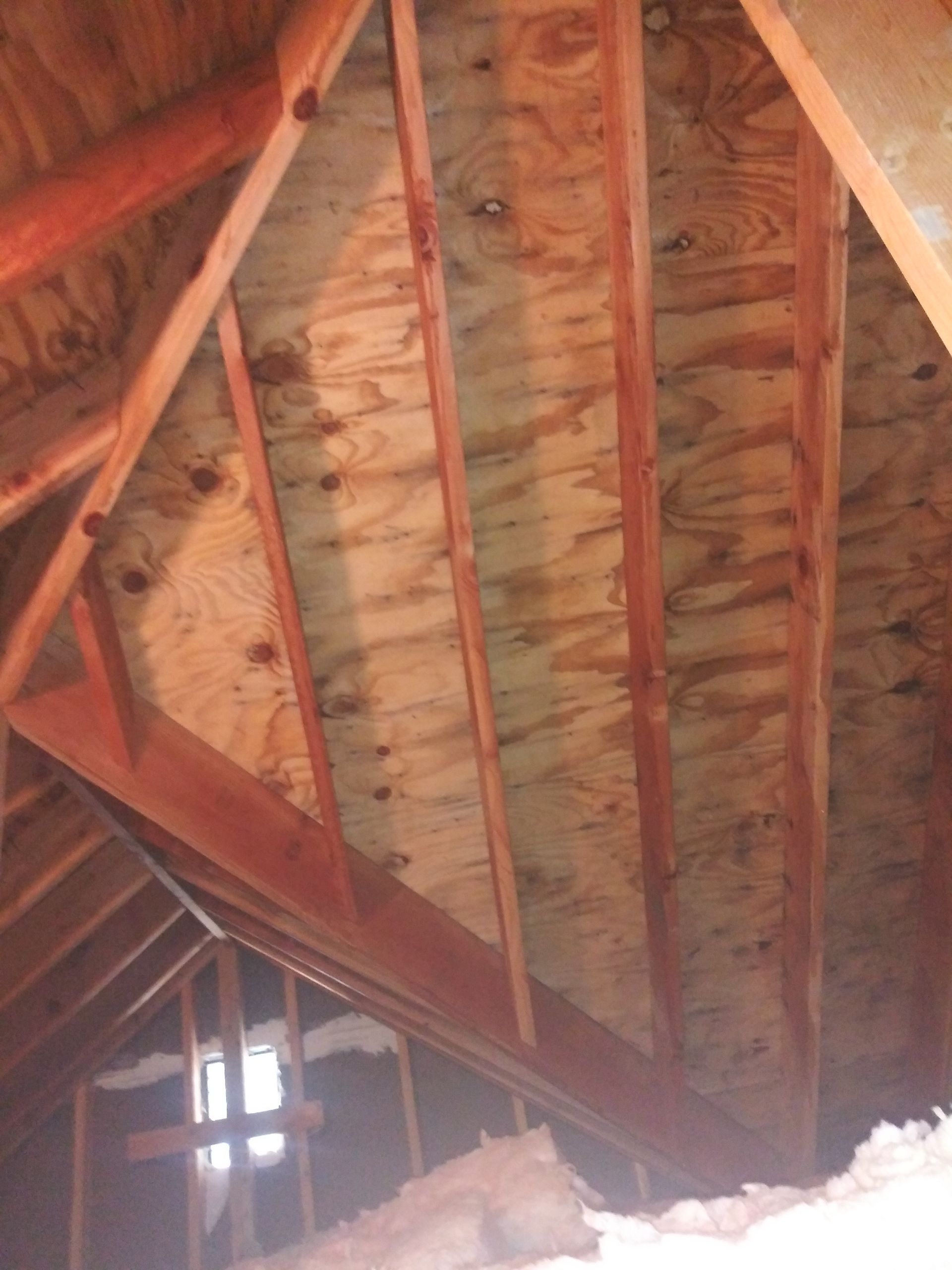 Looking up at the ceiling of an attic with wooden beams