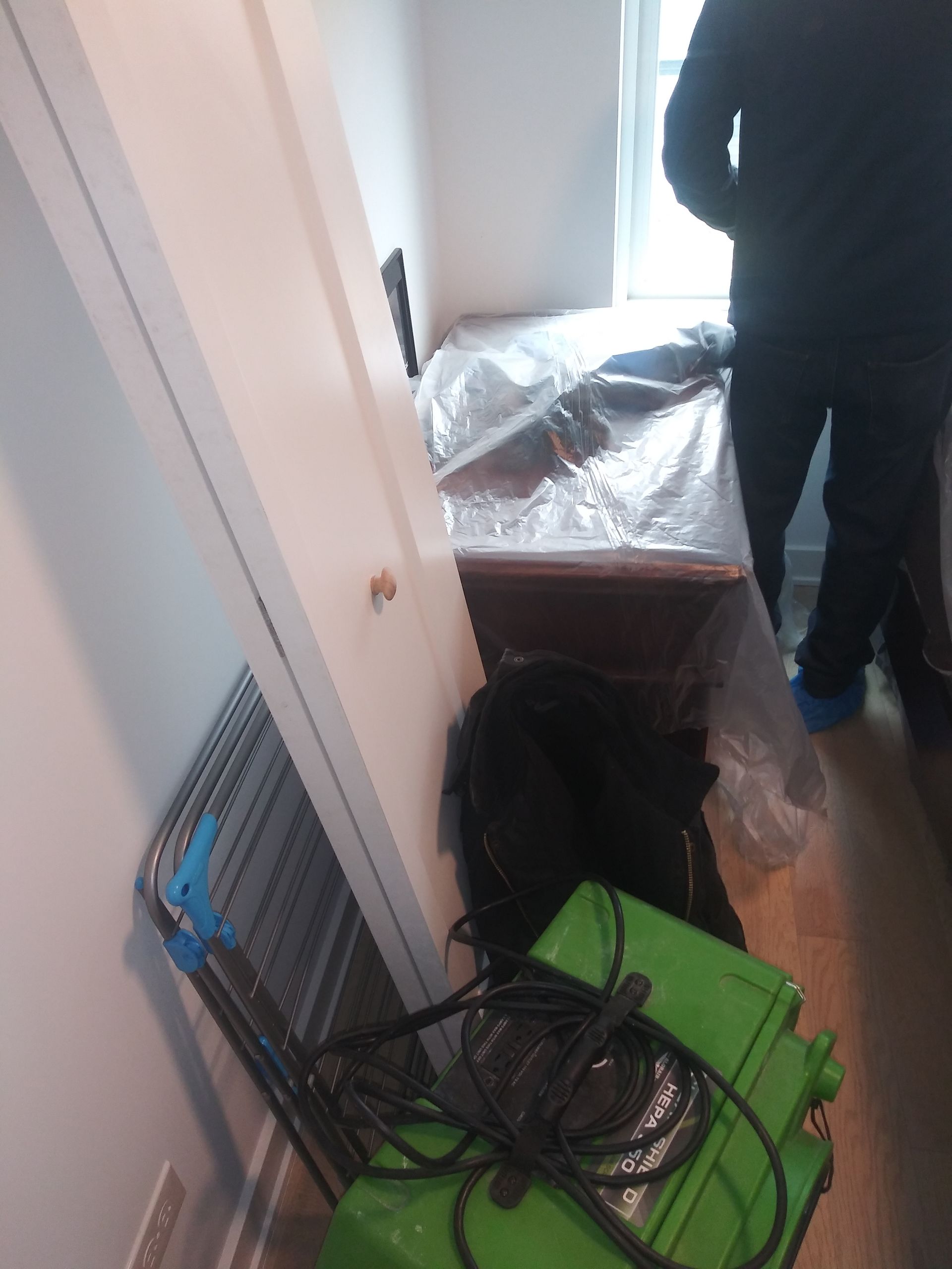 A person is standing in a room with a green box on the floor.