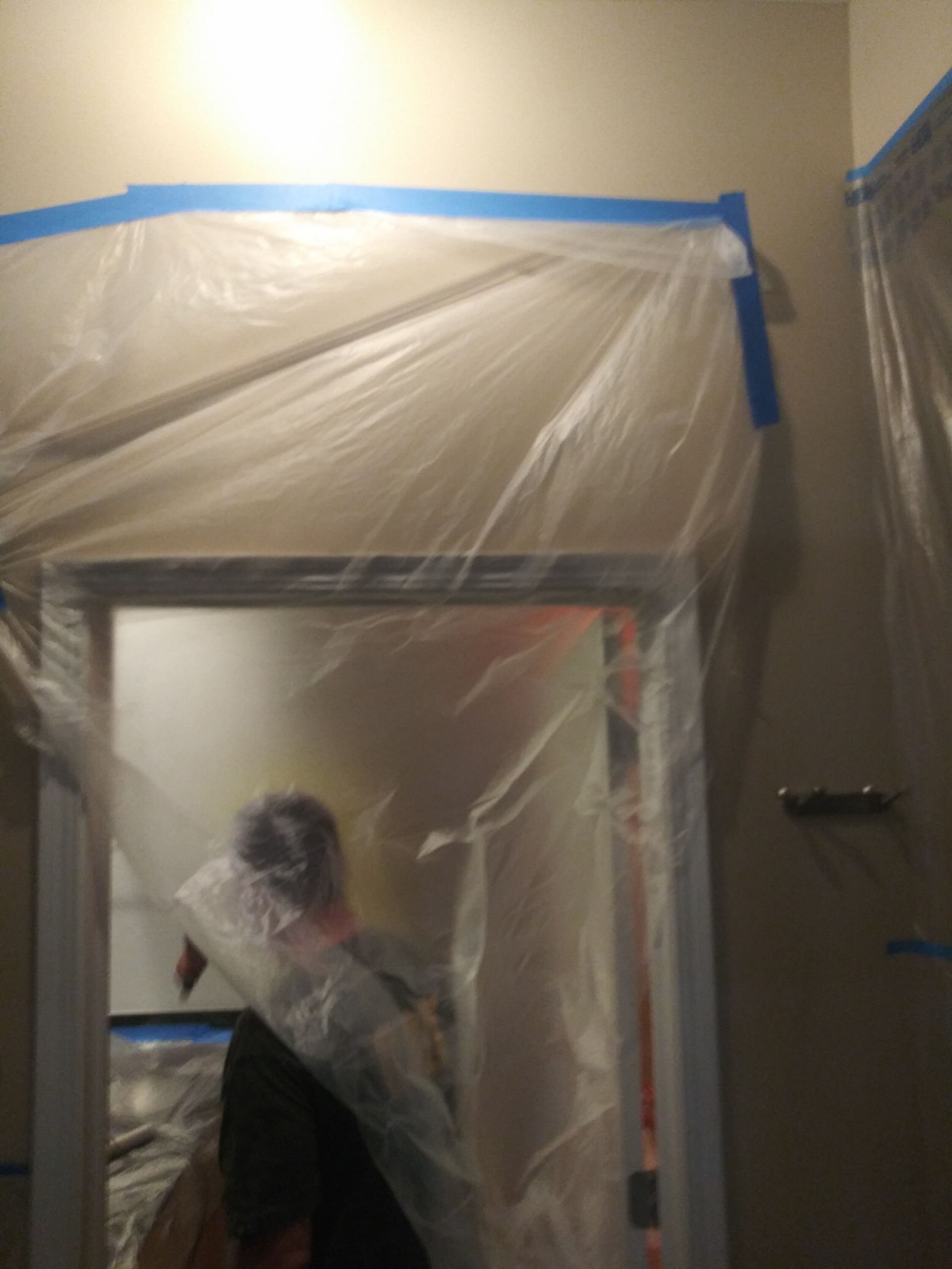 A person is standing in a room covered in plastic.