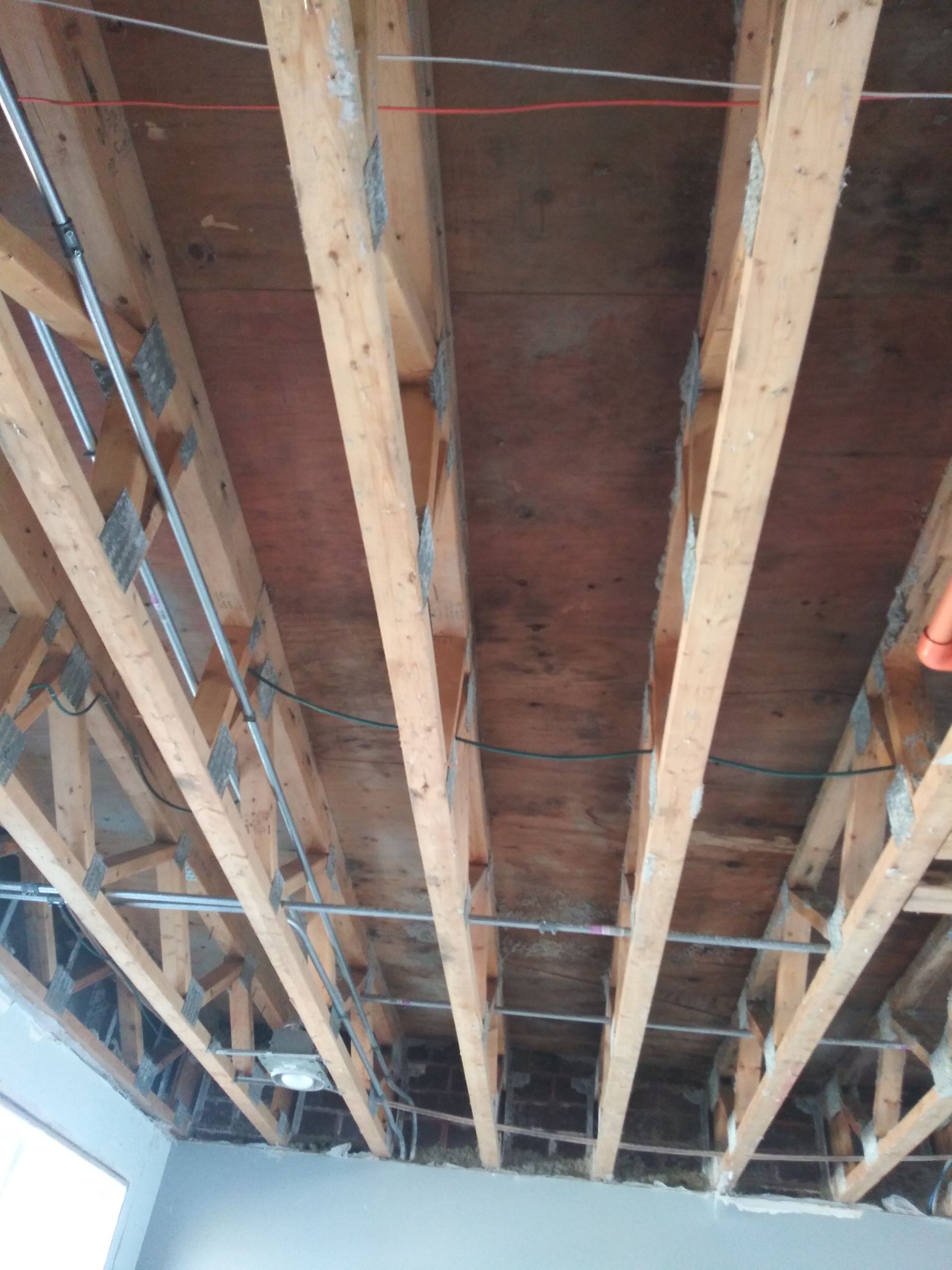 A ceiling with a lot of wooden beams and wires