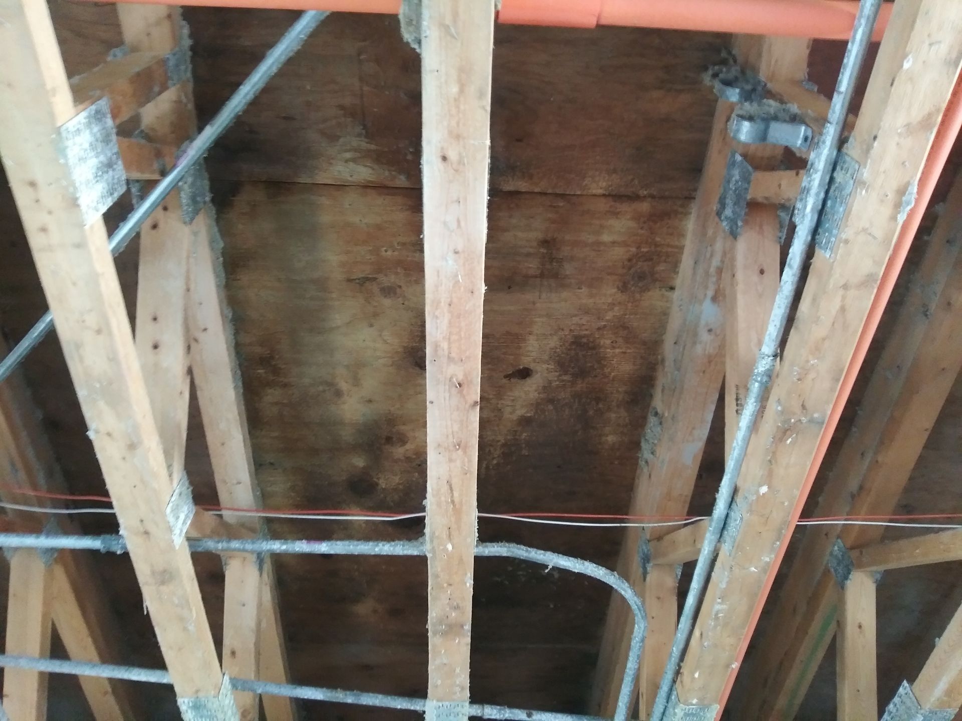 The ceiling of a building with wooden beams and wires