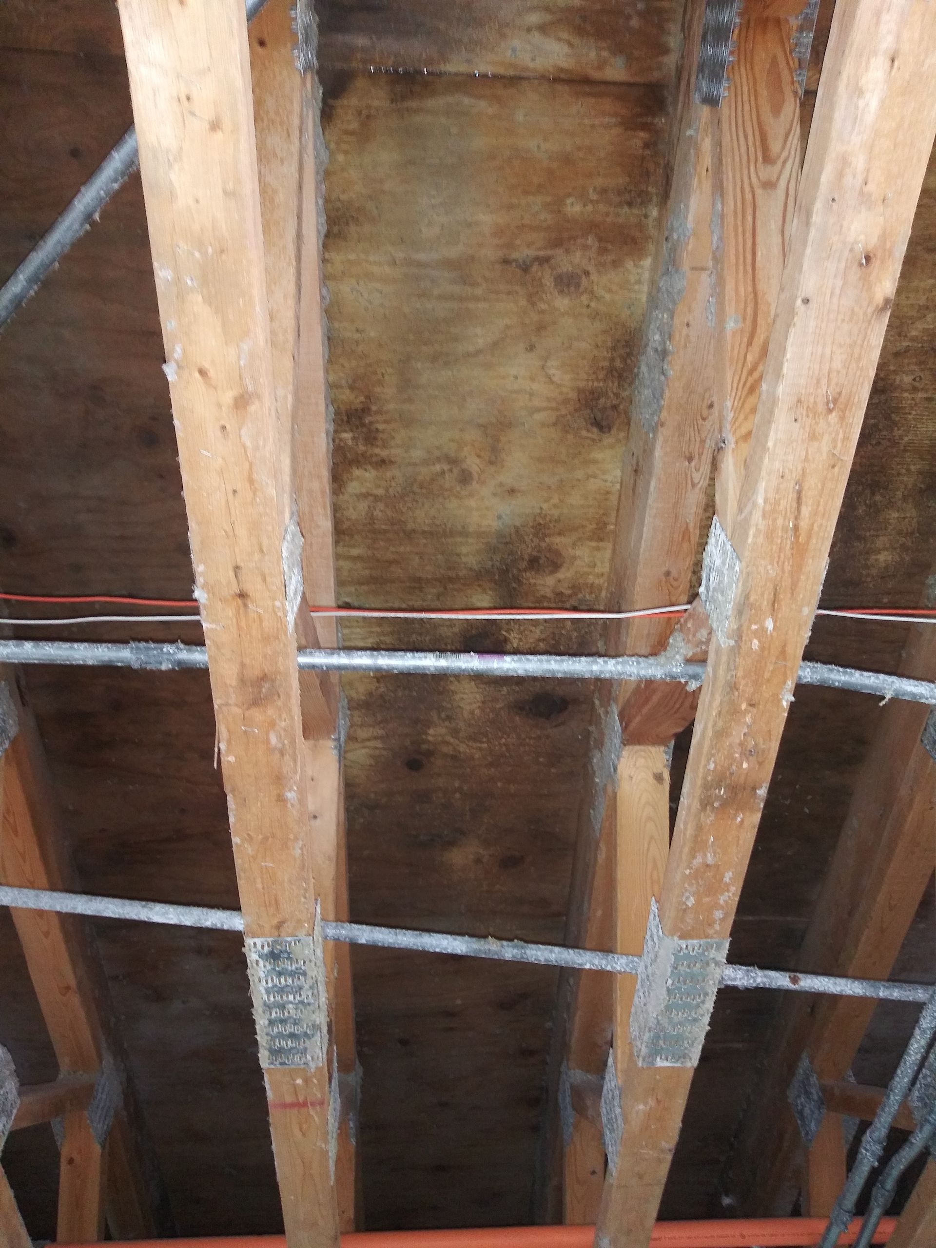 A ceiling with a lot of wooden beams and wires