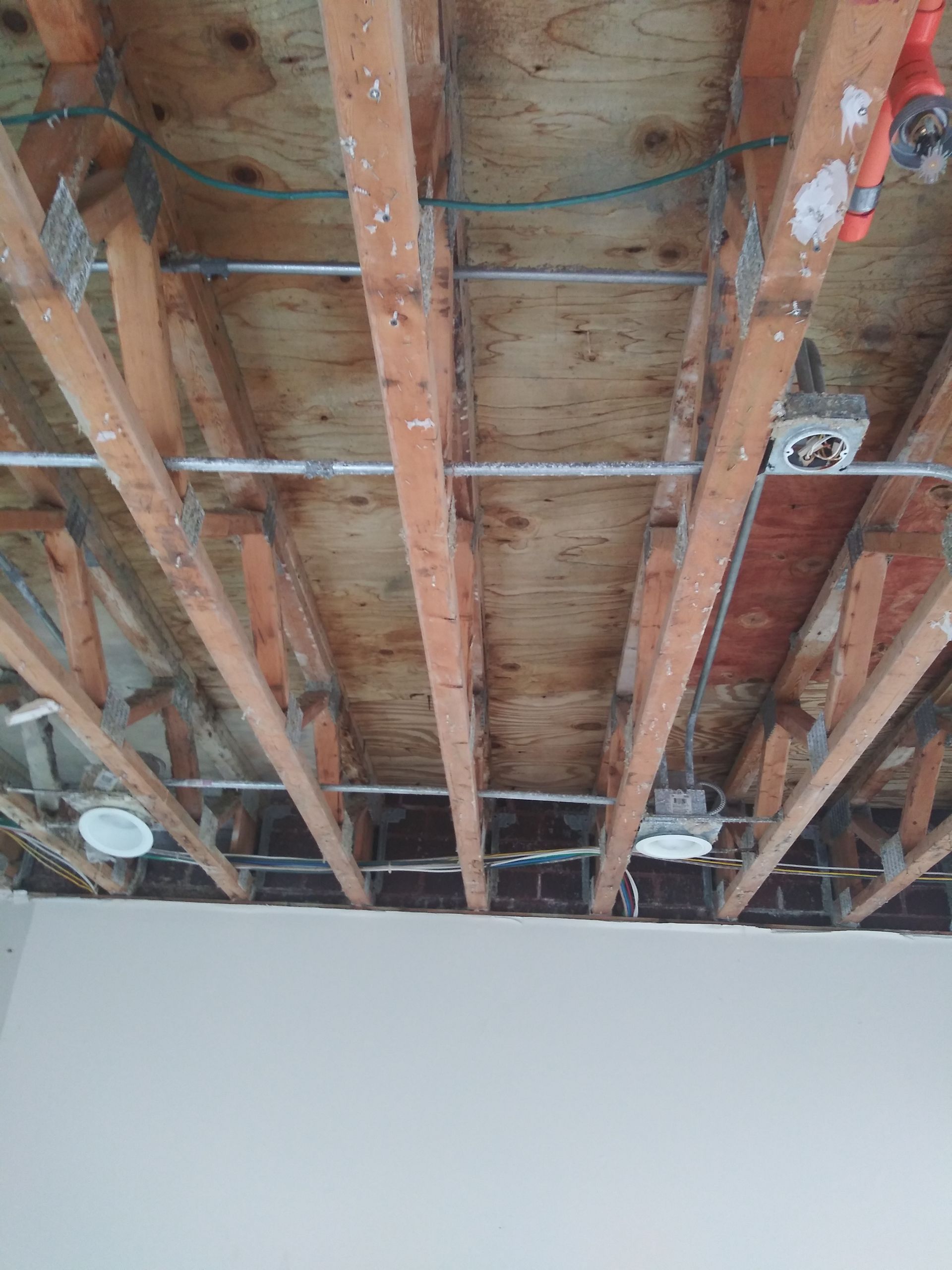 A ceiling with wooden beams and wires hanging from it.