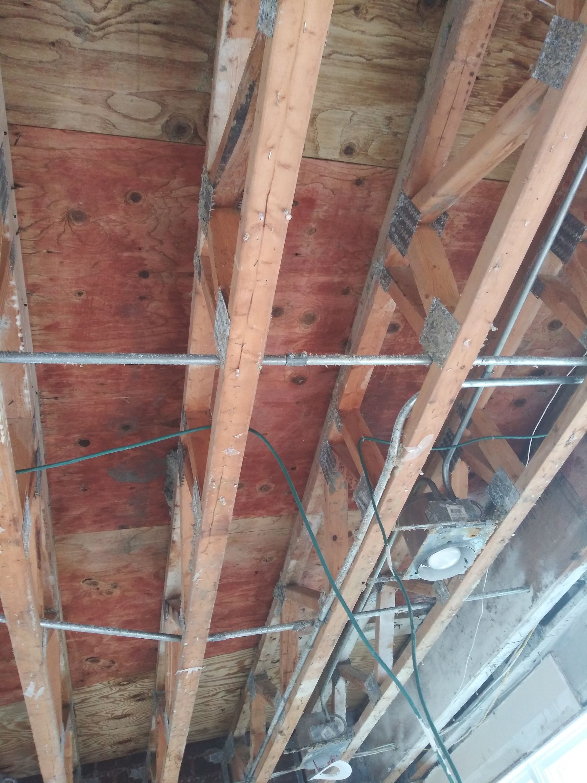 A ceiling with wooden beams and wires hanging from it.