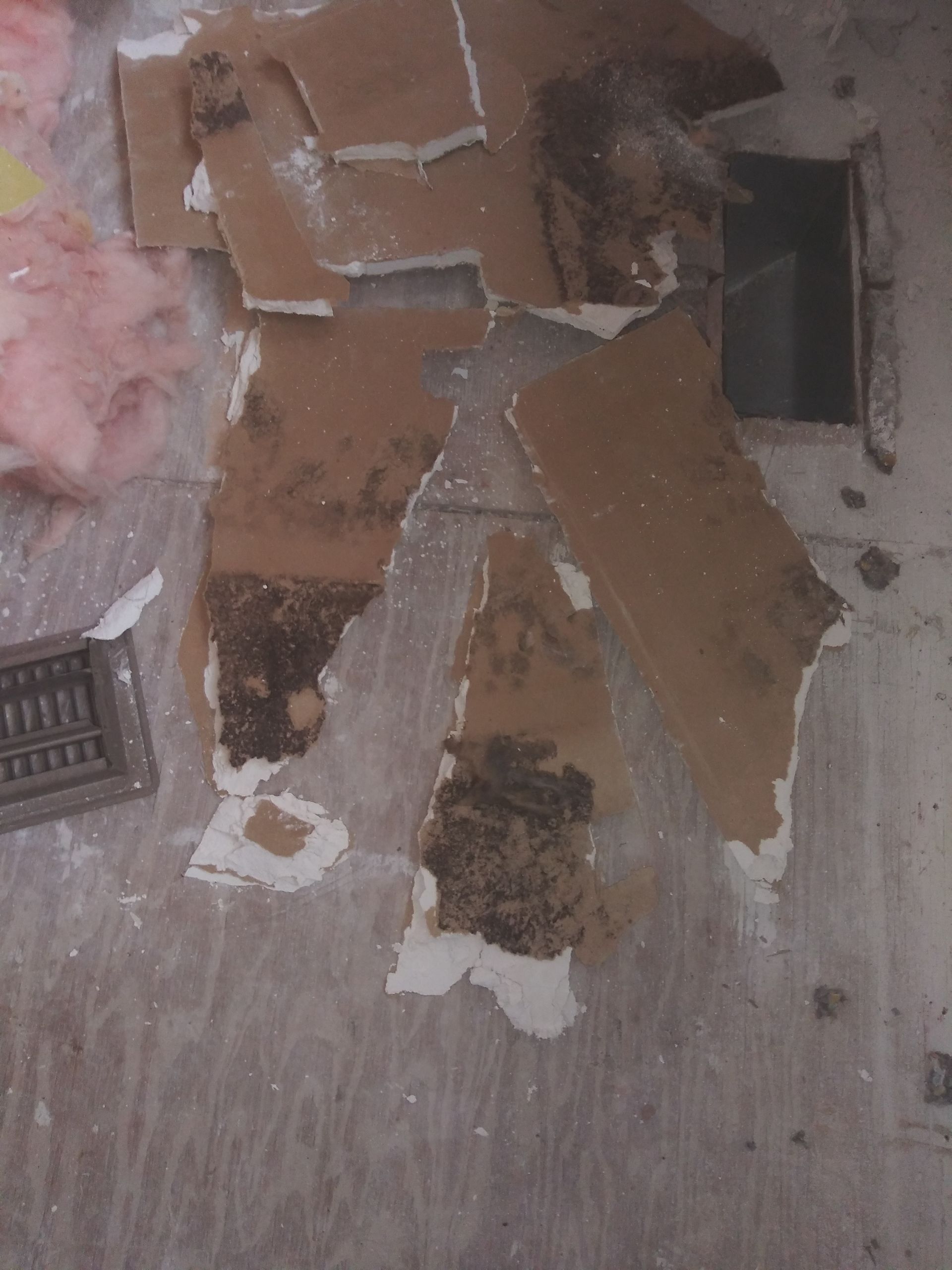 A piece of cardboard is laying on the floor next to a vent