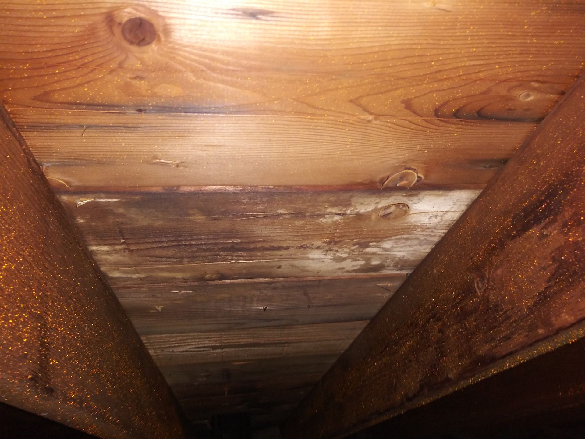 A close up of a wooden ceiling with a few holes in it.