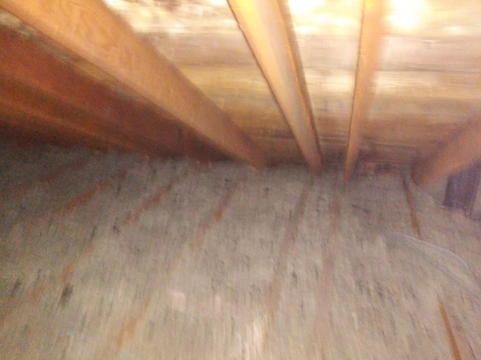 An attic with wooden beams and a wooden floor.