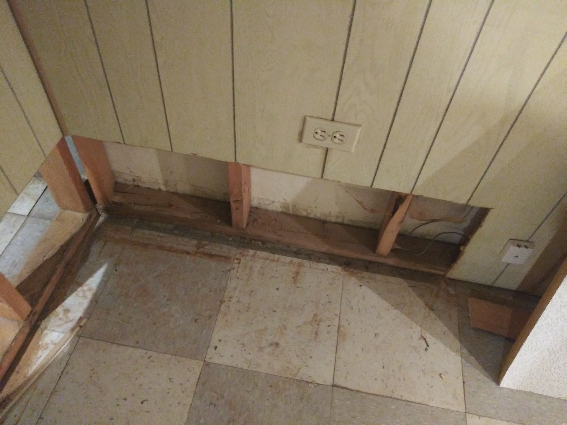 A room with a hole in the wall and a tiled floor.