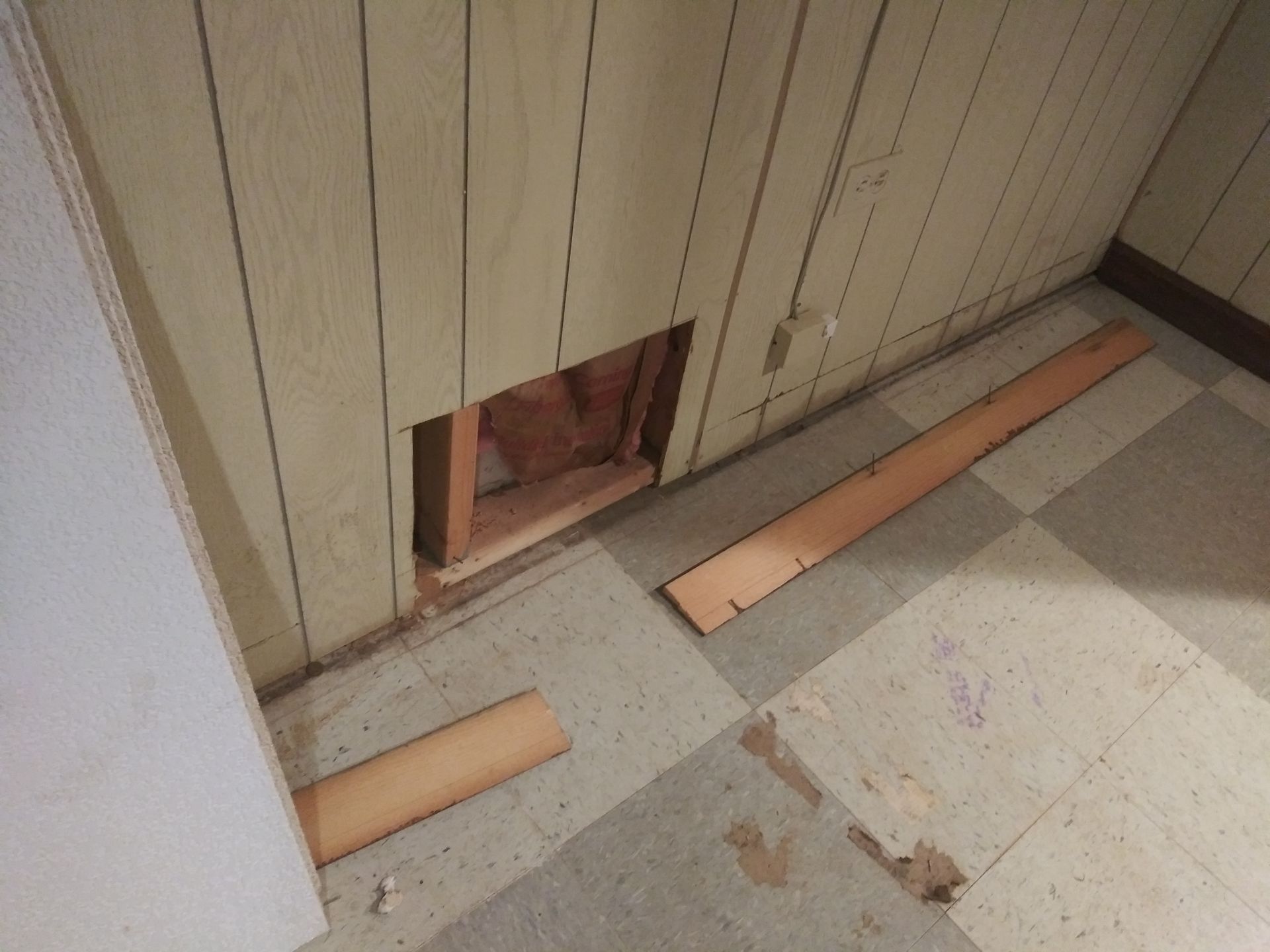 A room with a hole in the wall and a piece of wood on the floor