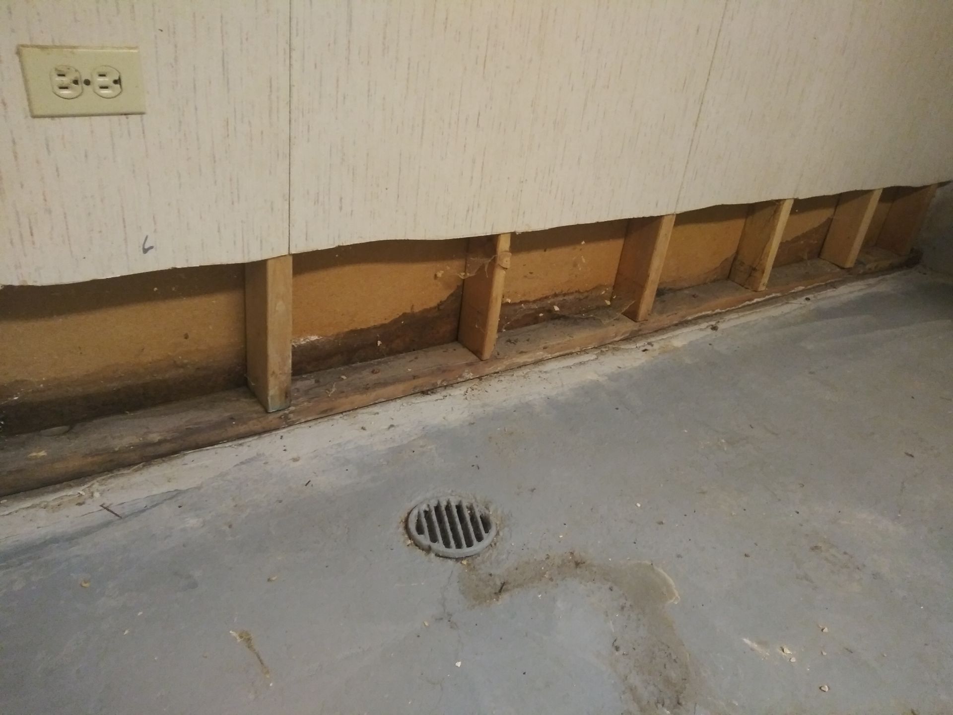 There is a drain on the floor next to a wall.