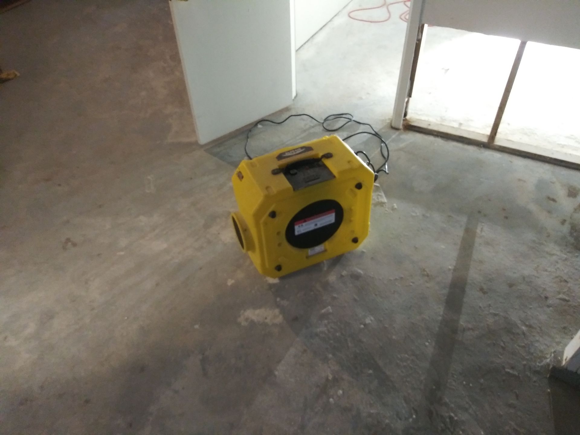 A yellow device is sitting on a concrete floor