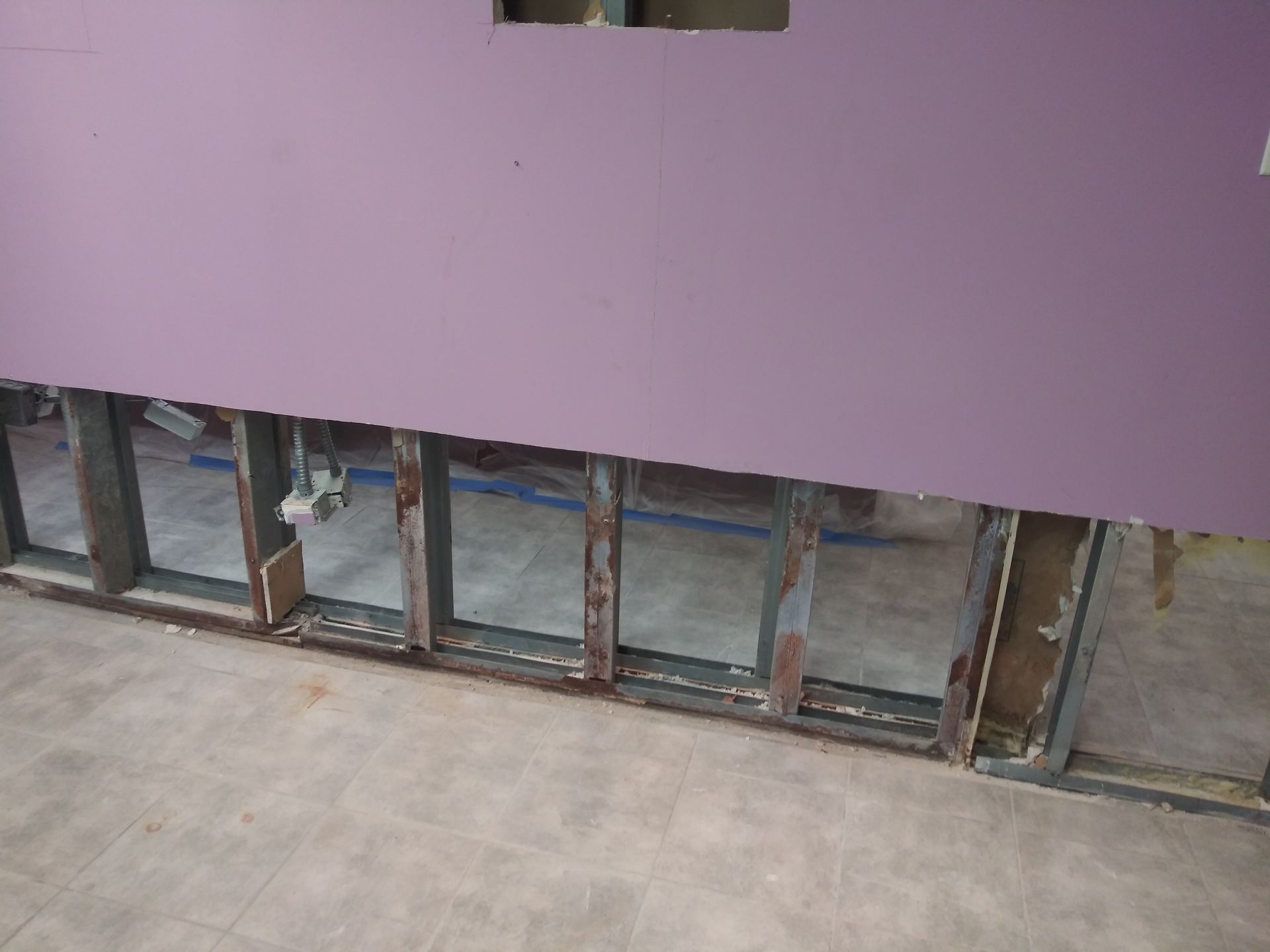 A purple wall with a hole in it is being remodeled.