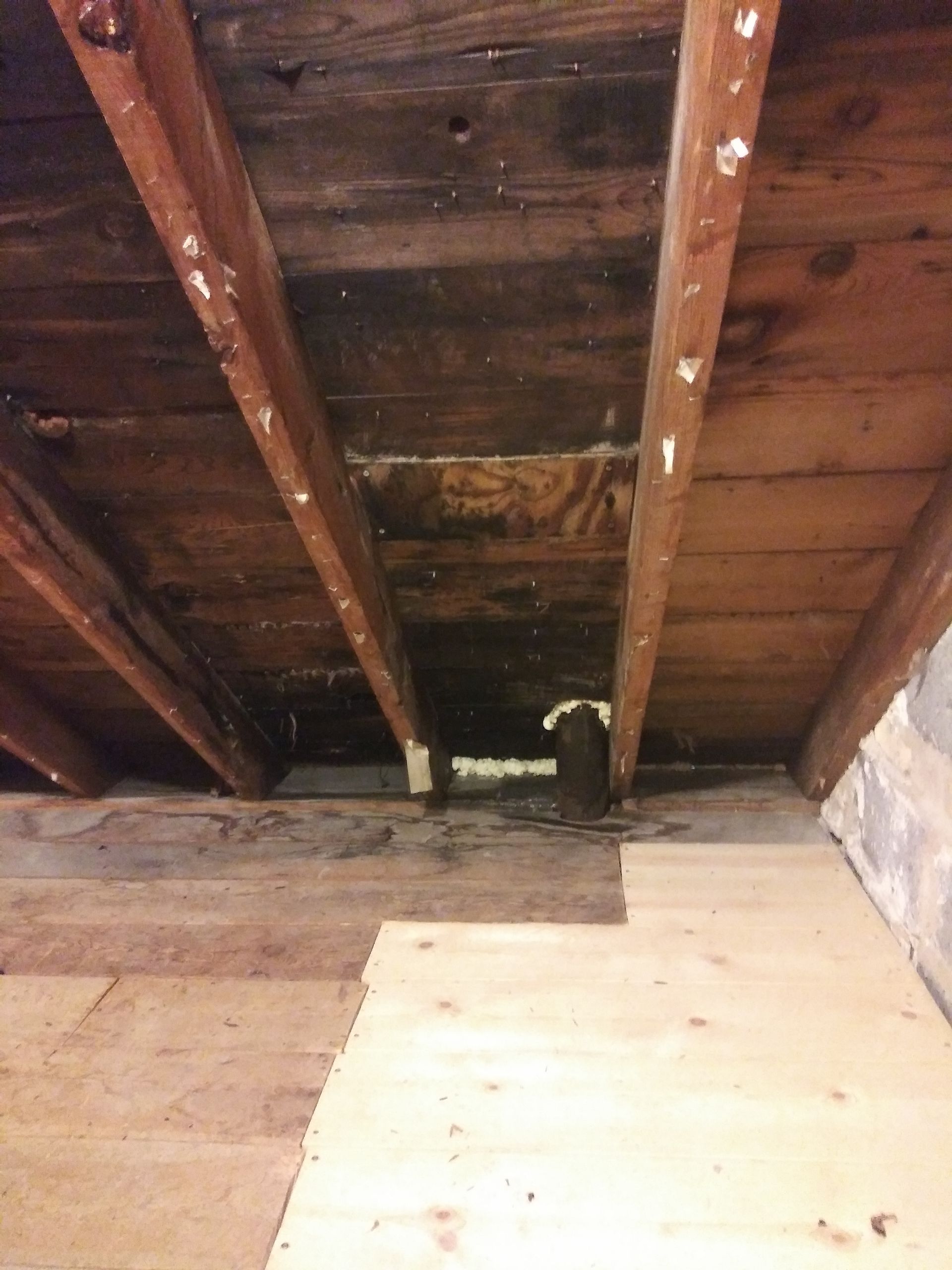A wooden ceiling with a hole in it and a wooden floor.