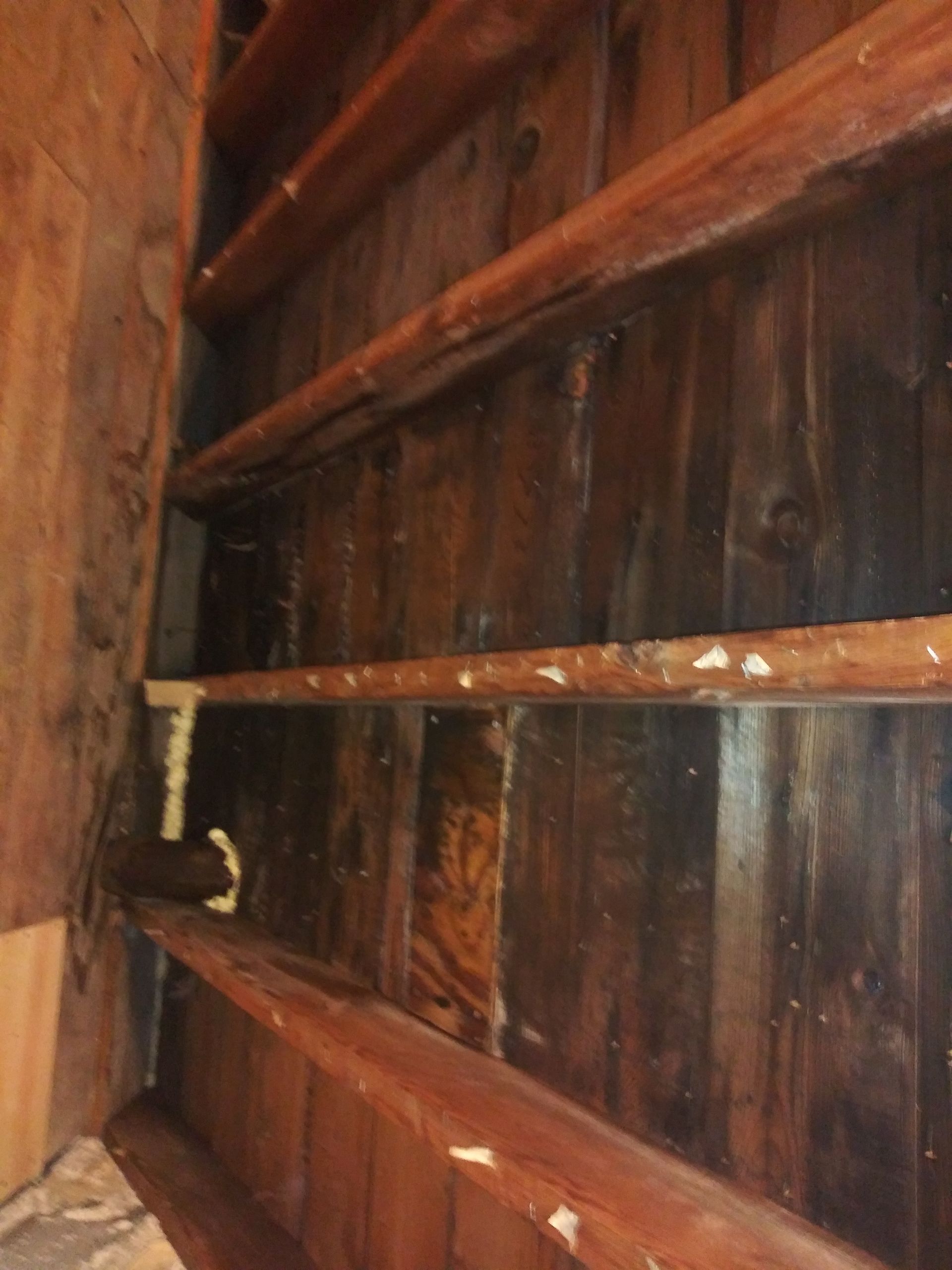 A close up of a wooden wall with shelves in a room.