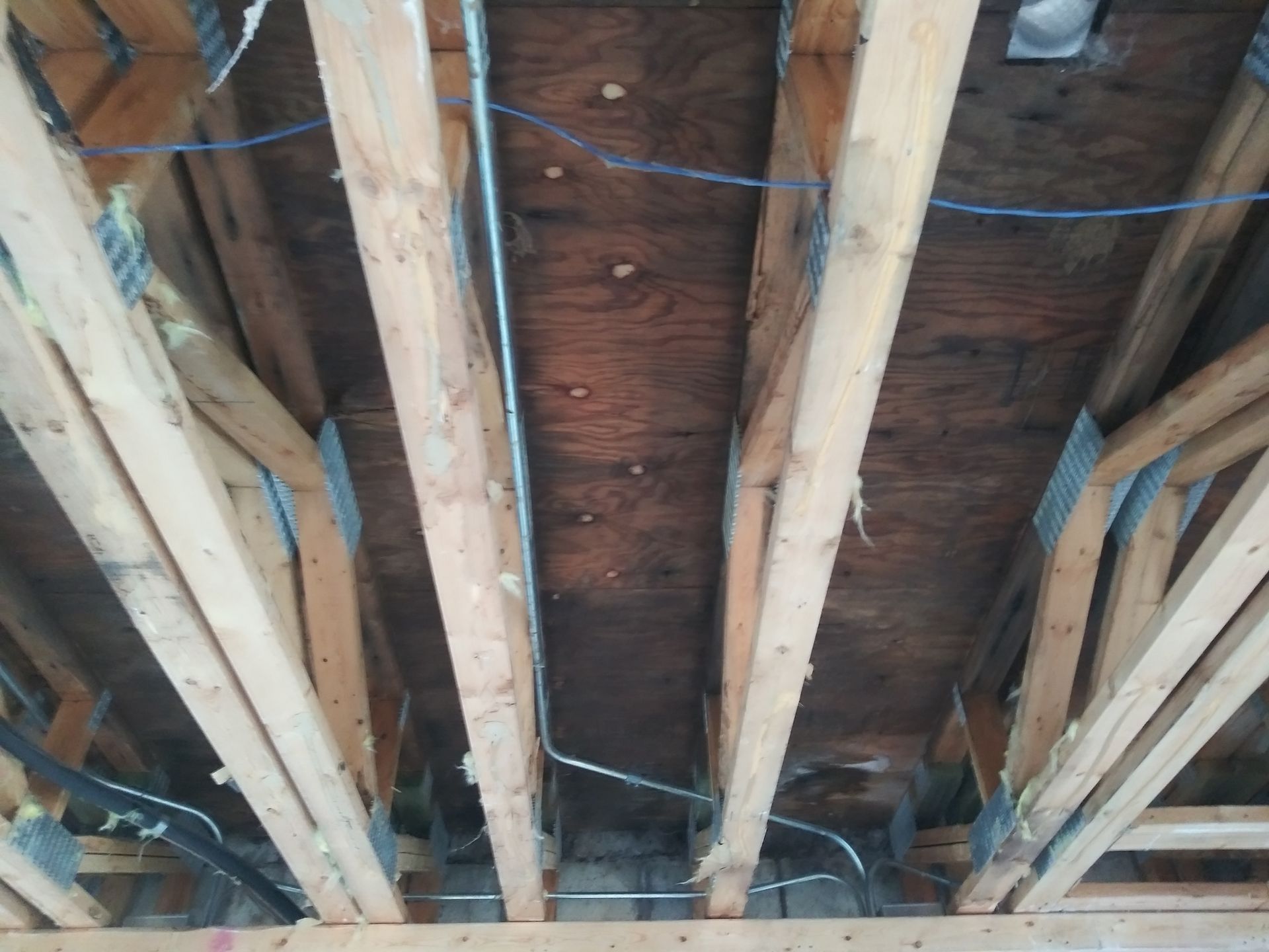 A ceiling with a lot of wooden beams and wires
