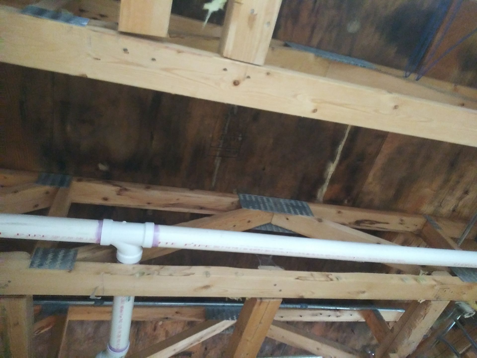 A white pipe is hanging from the ceiling of a wooden structure.