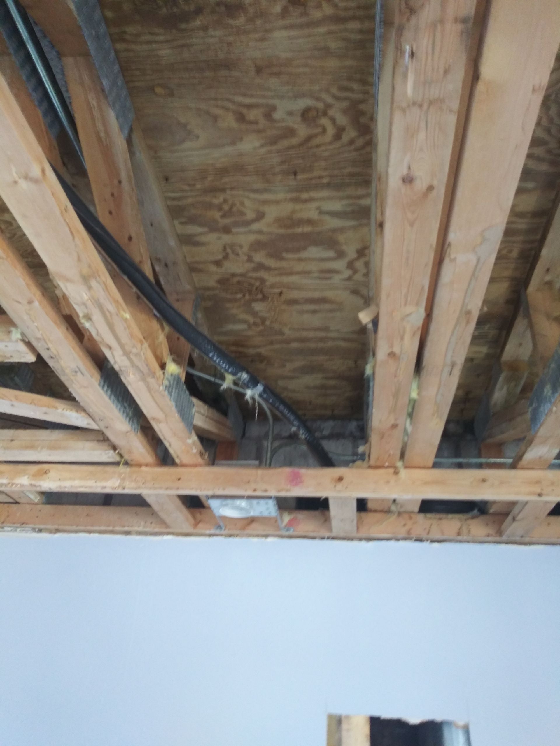 A ceiling with wooden beams and pipes coming out of it.