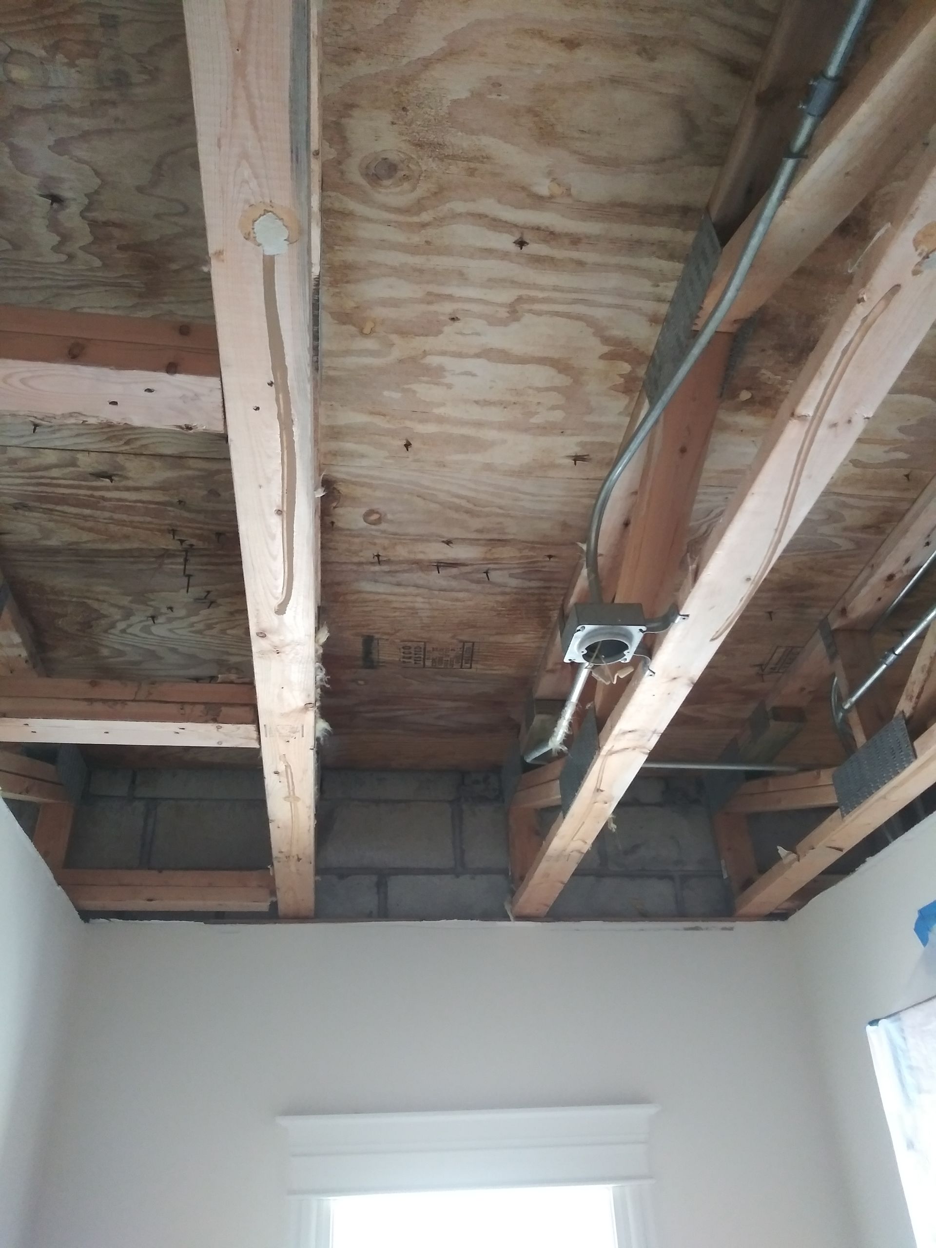 The ceiling of a room with wooden beams and a window.