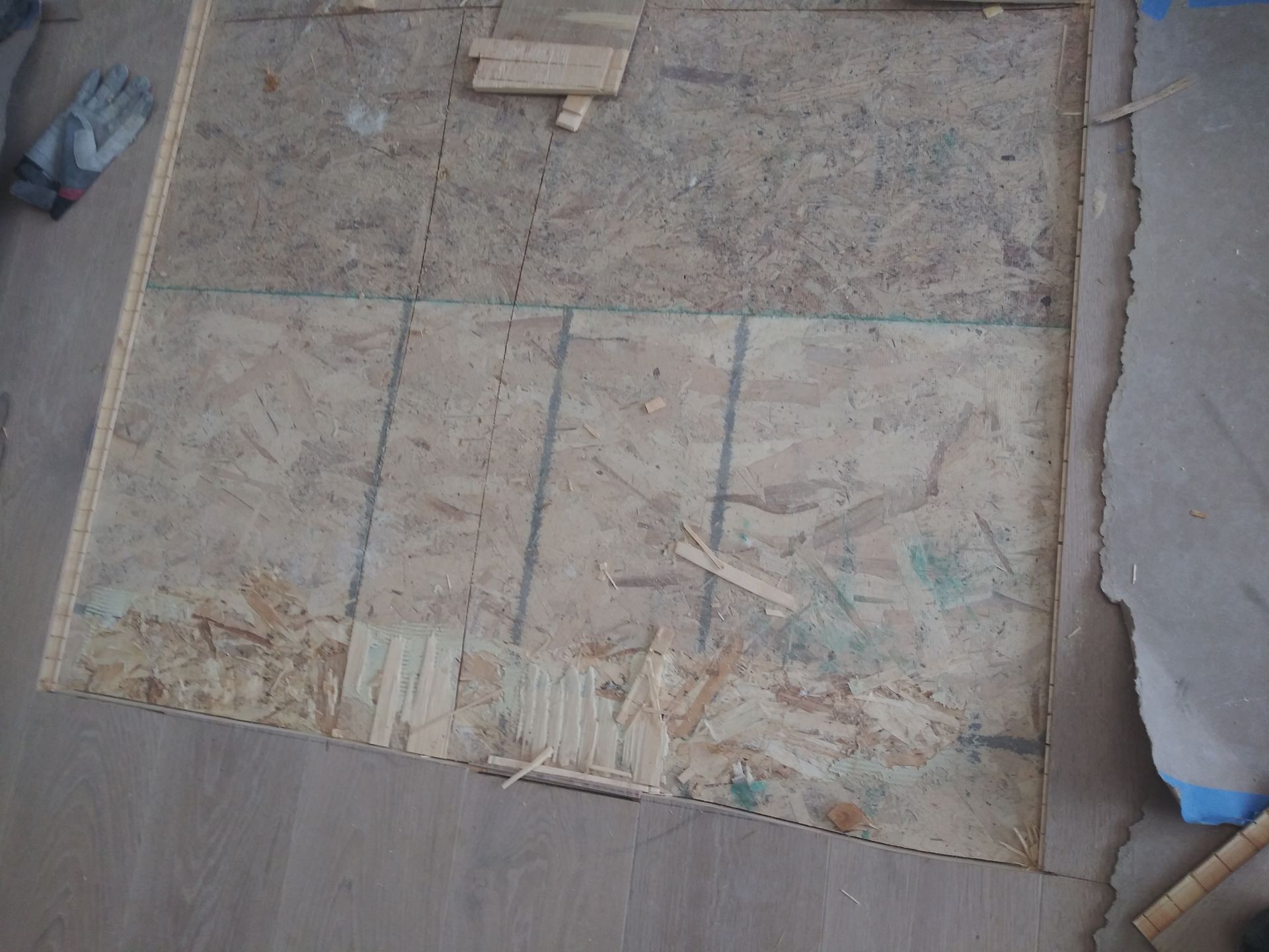 A piece of plywood is laying on a wooden floor.