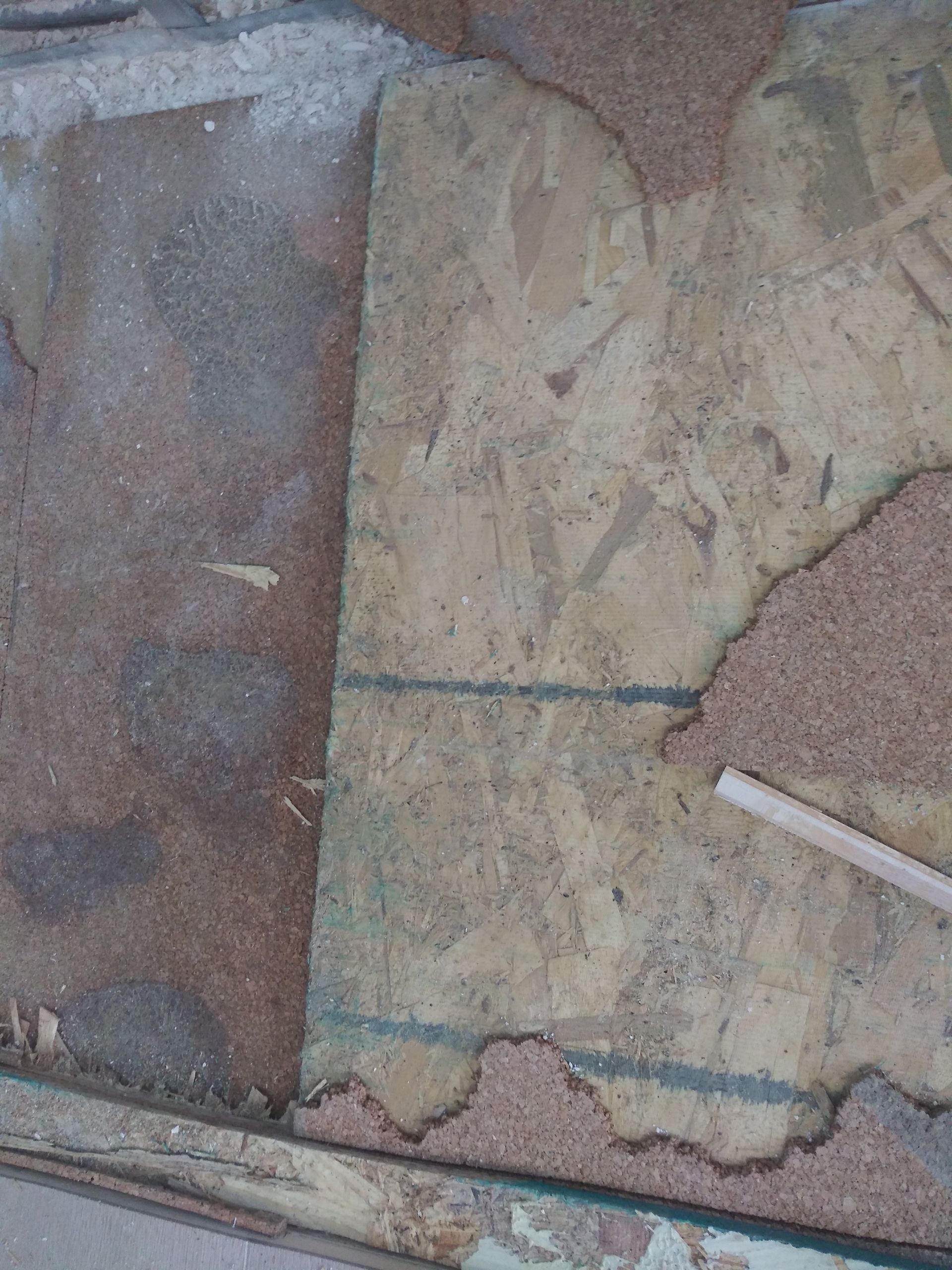 A piece of plywood is laying on the ground next to a piece of wood.