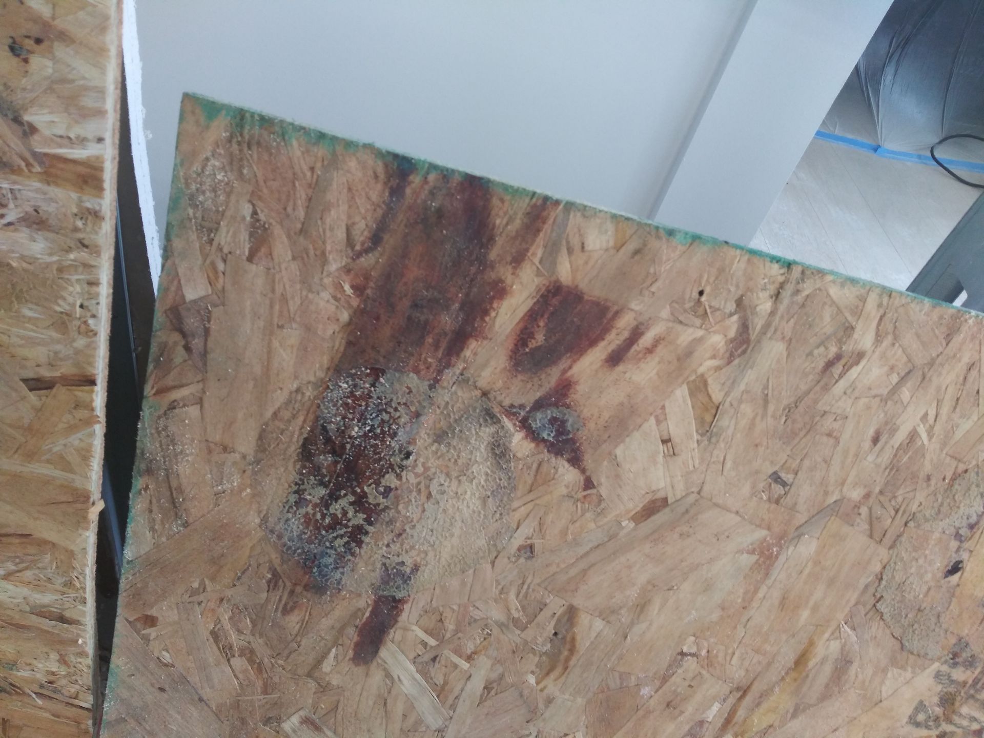 A piece of plywood is sitting on the floor next to a wall.