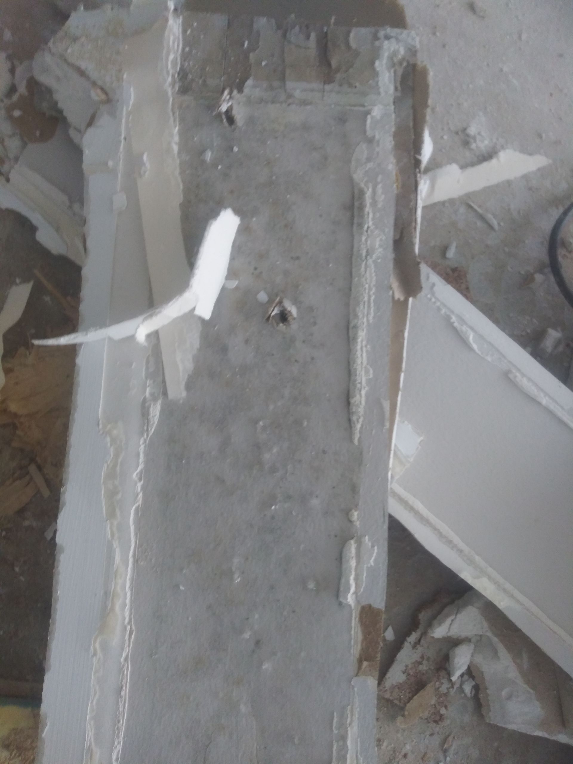 A concrete wall with a hole in it and a piece of paper sticking out of it.