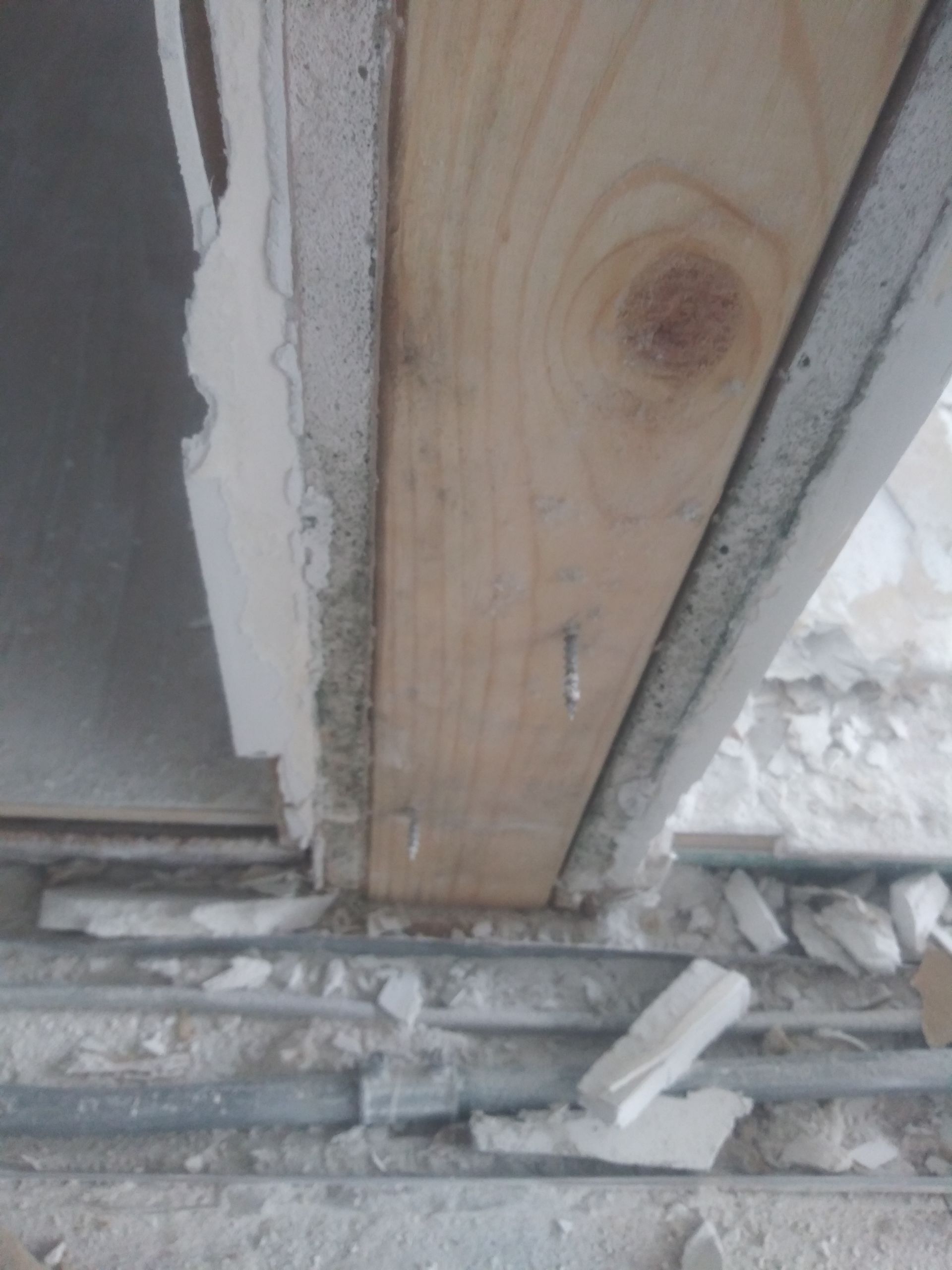 A close up of a wooden beam with a screw in it.