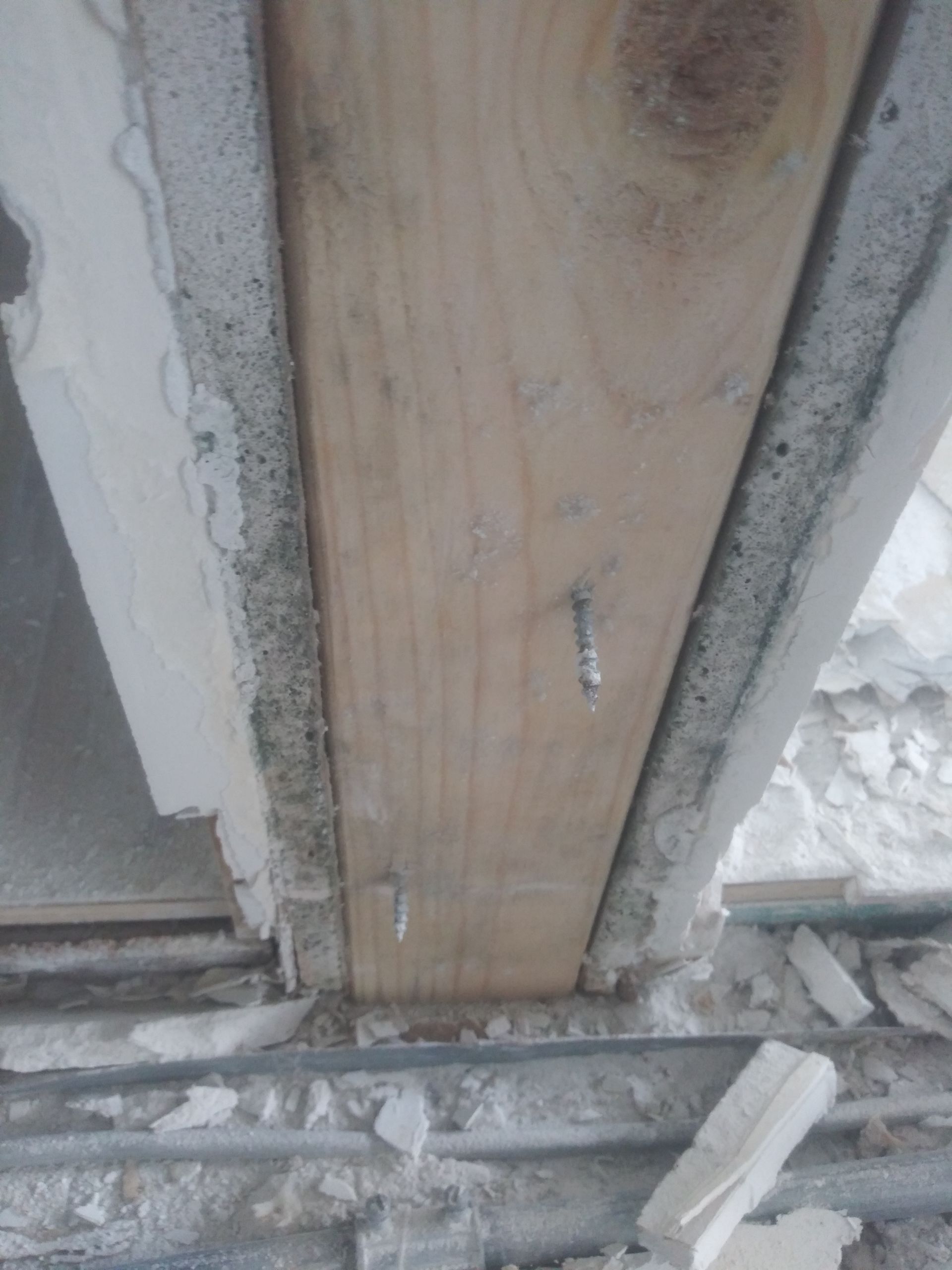 A close up of a wooden beam with a screw in it.