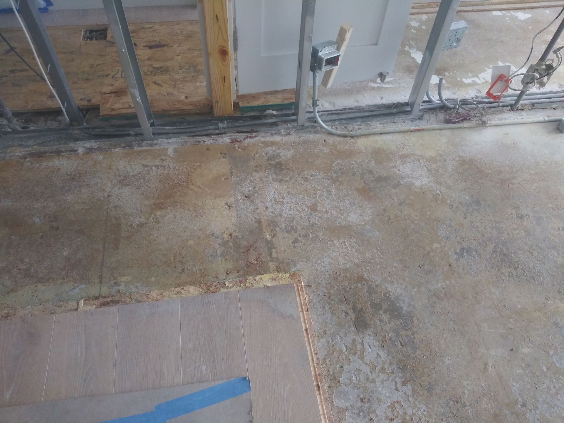 A concrete floor with a blue tape on it in a room under construction.