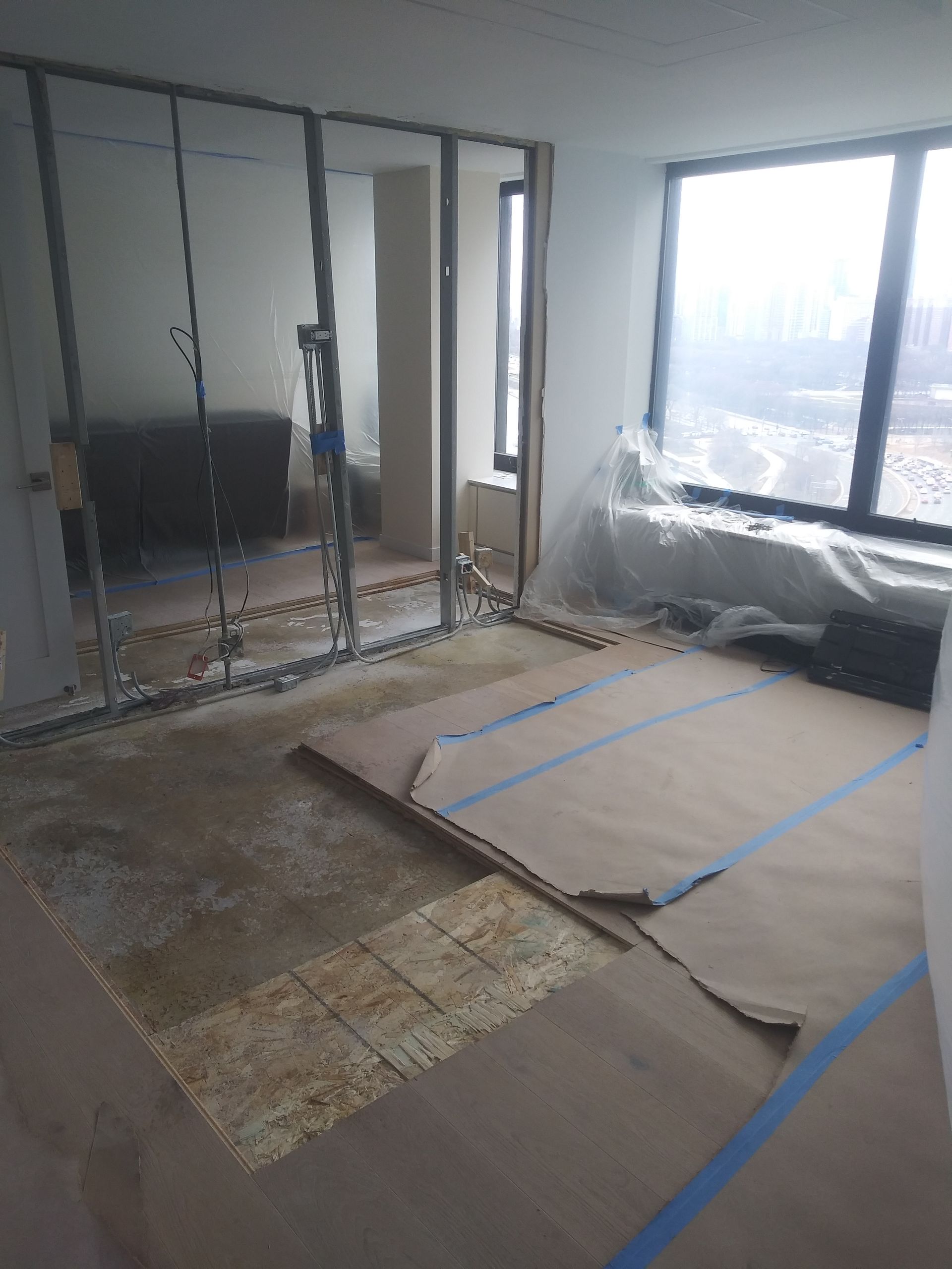 A room with a lot of windows and a lot of cardboard on the floor.