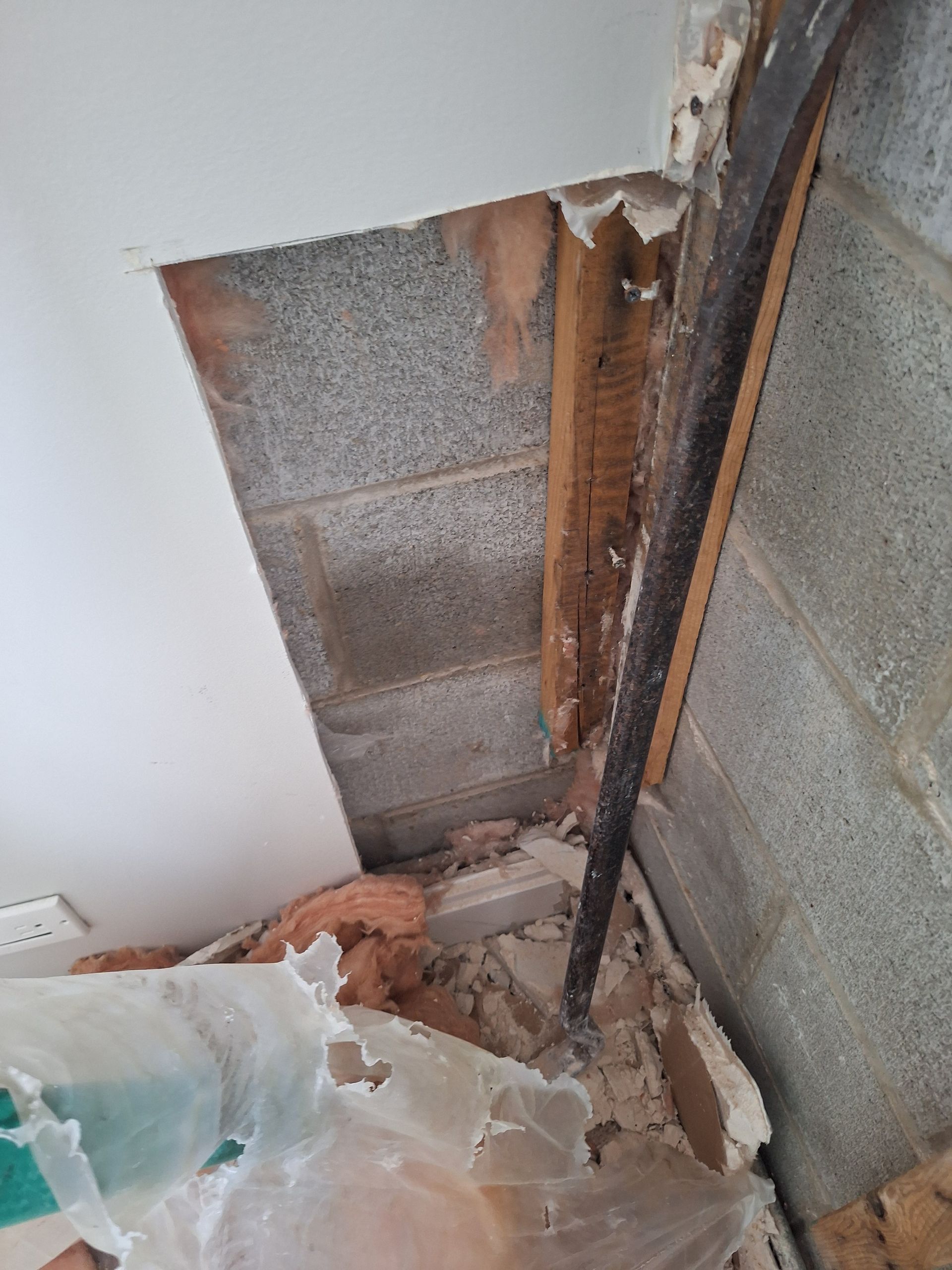 Damaged ceiling showing exposed wooden beam, concrete blocks, and insulation.