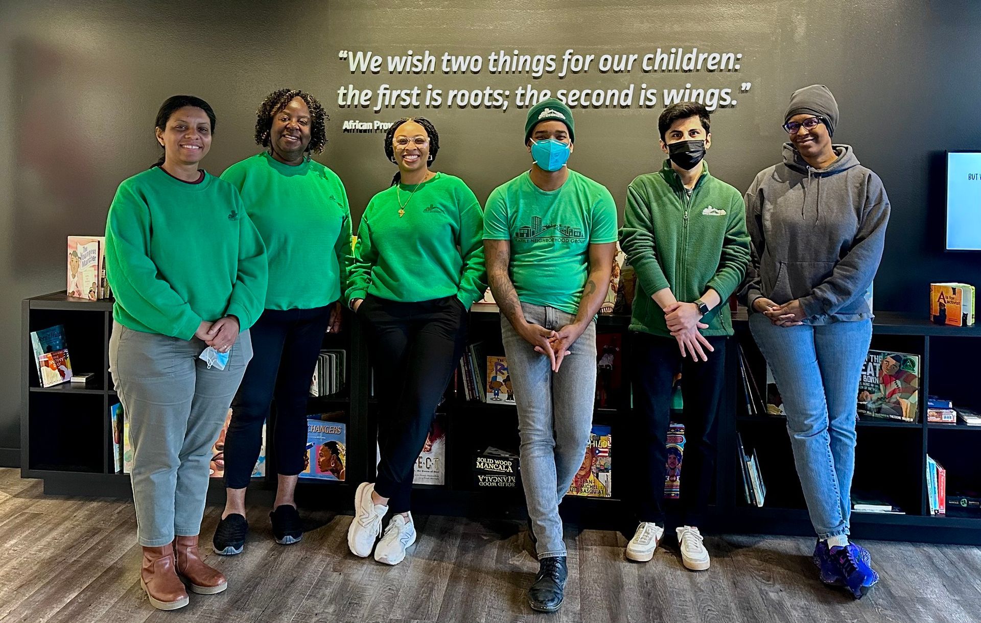 A group of people wearing green shirts and masks are posing for a picture.