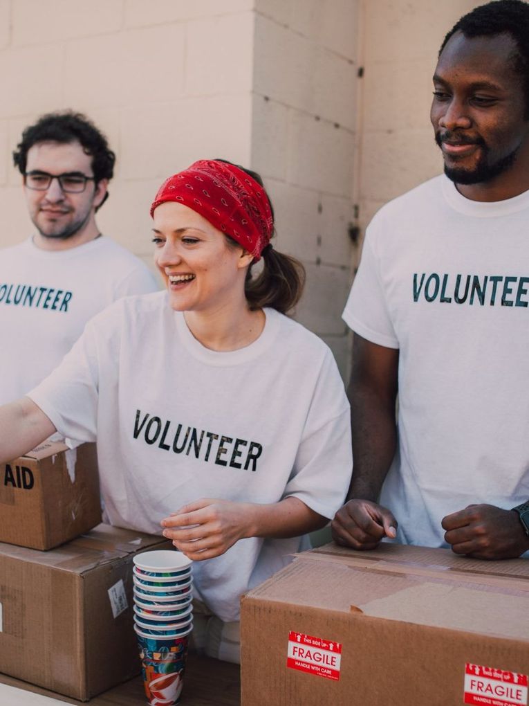 A group of people wearing volunteer shirts are standing around boxes.