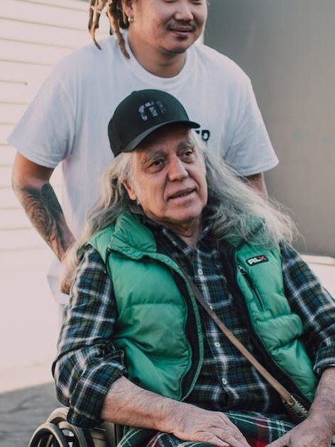 A man in a white shirt is standing next to a man in a green vest.