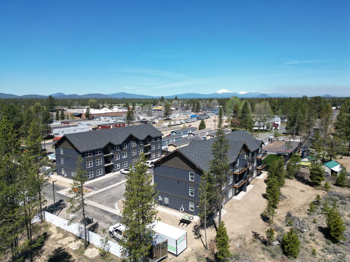 An aerial view of a large apartment building surrounded by trees and mountains.