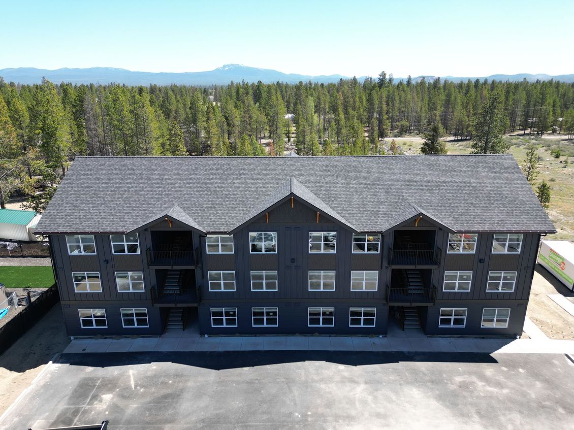 An aerial view of a large apartment building in the middle of a forest.
