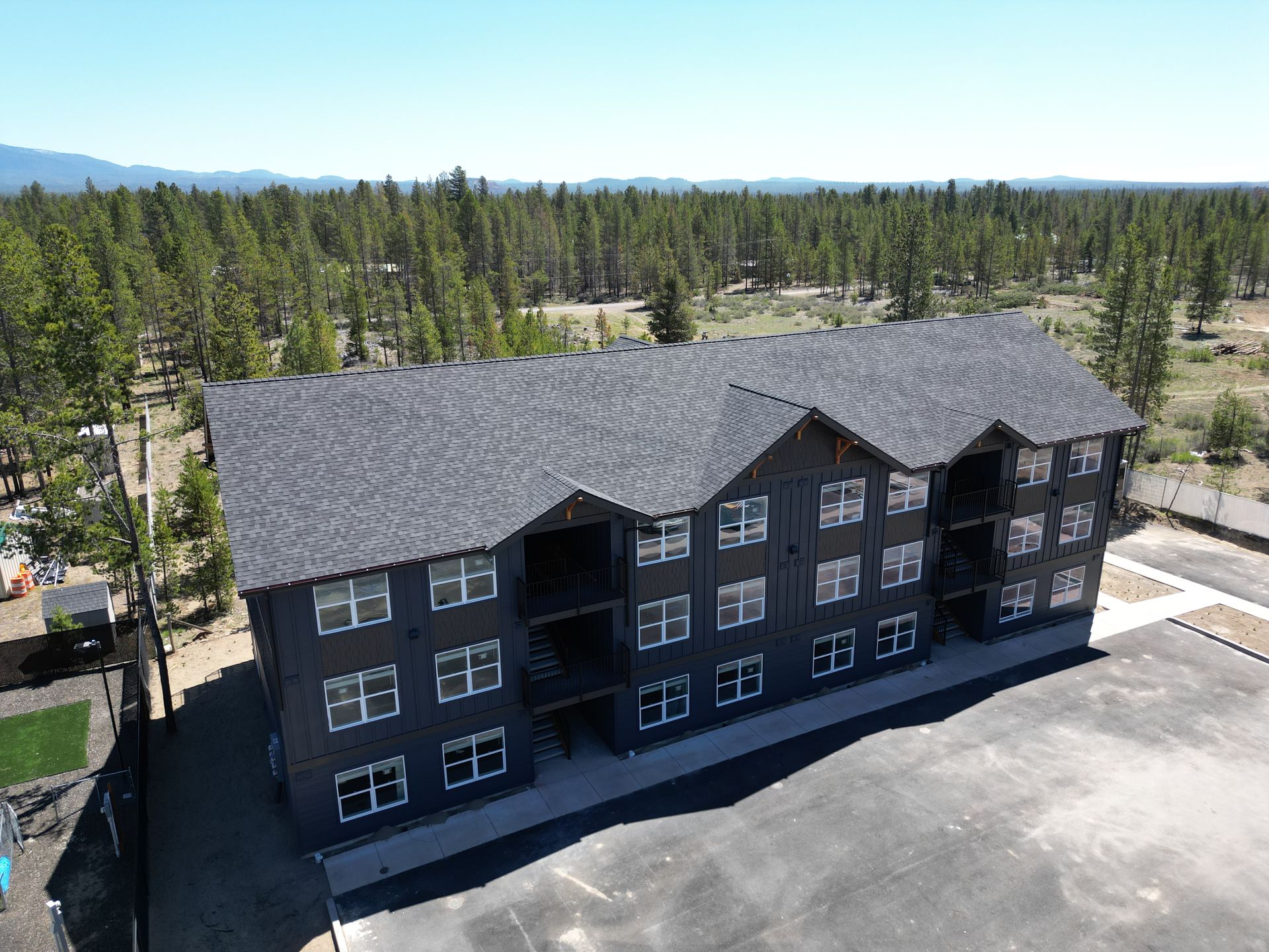 An aerial view of a large apartment building in the middle of a forest.