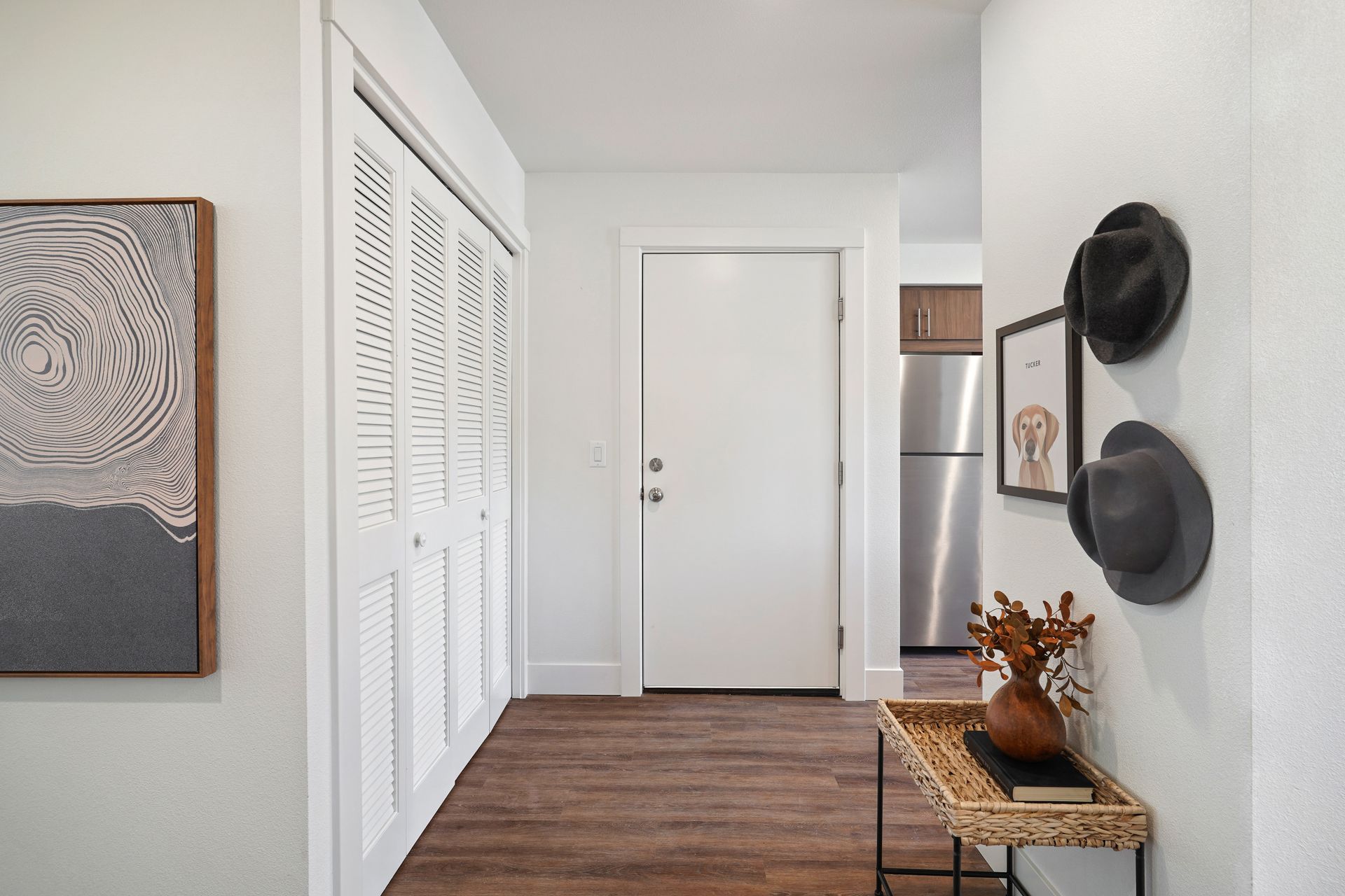 A hallway in a house with a wicker table and hats hanging on the wall.