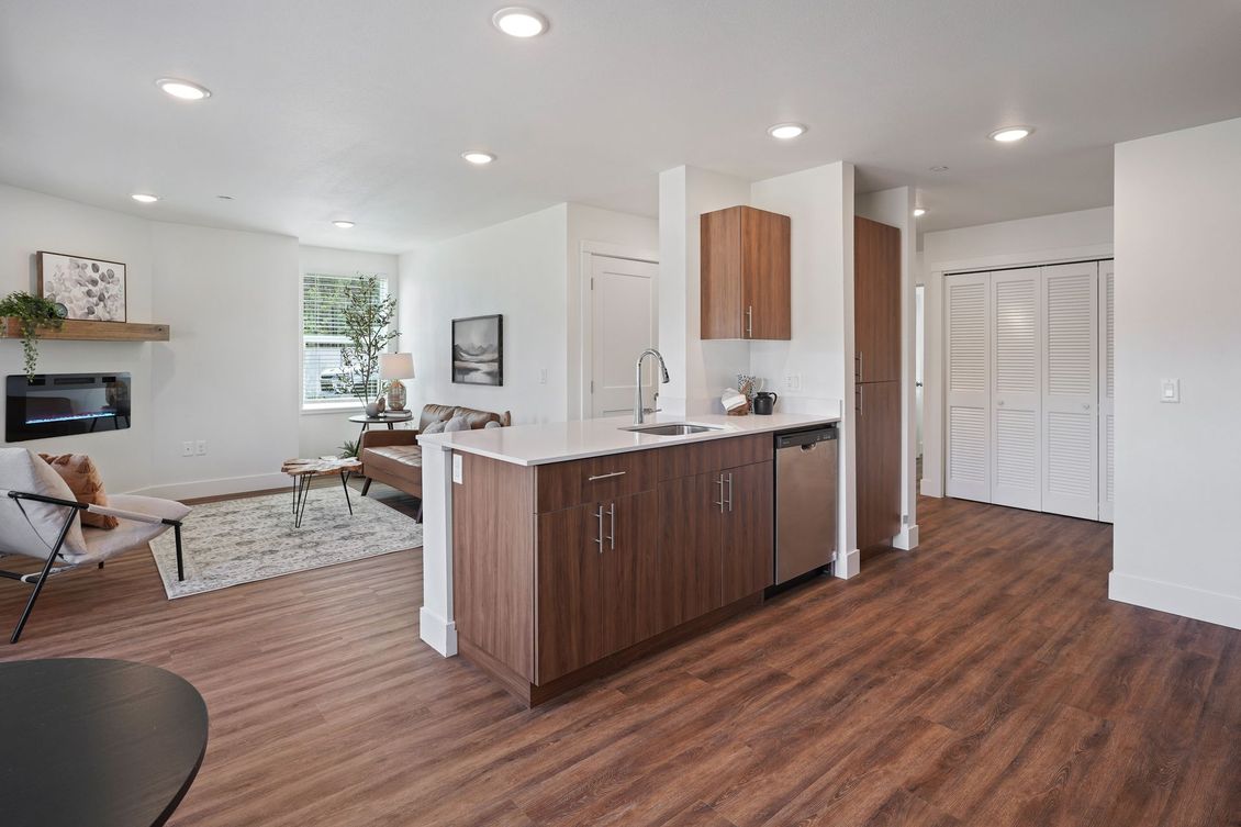 A living room and kitchen in a house with hardwood floors.
