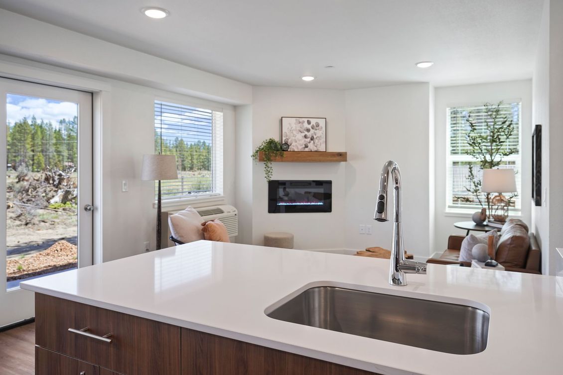 A kitchen with a sink and a fireplace in the background.