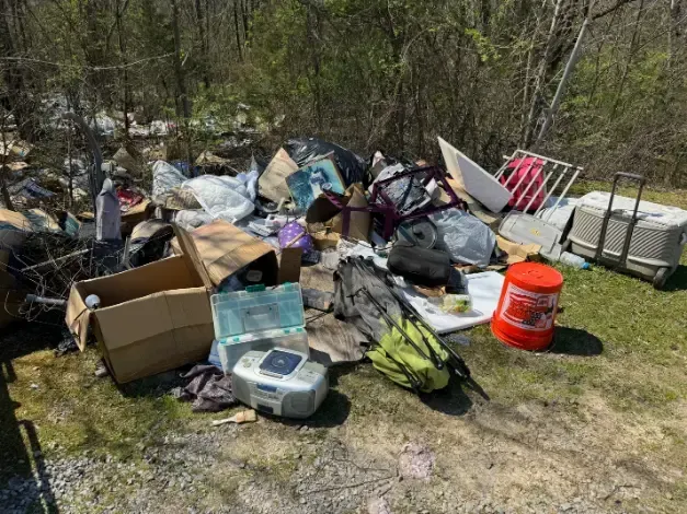 A pile of trash is sitting on the ground in the woods.