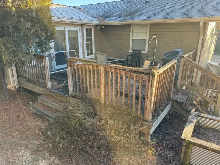 A house with a wooden deck and stairs in front of it before demolition