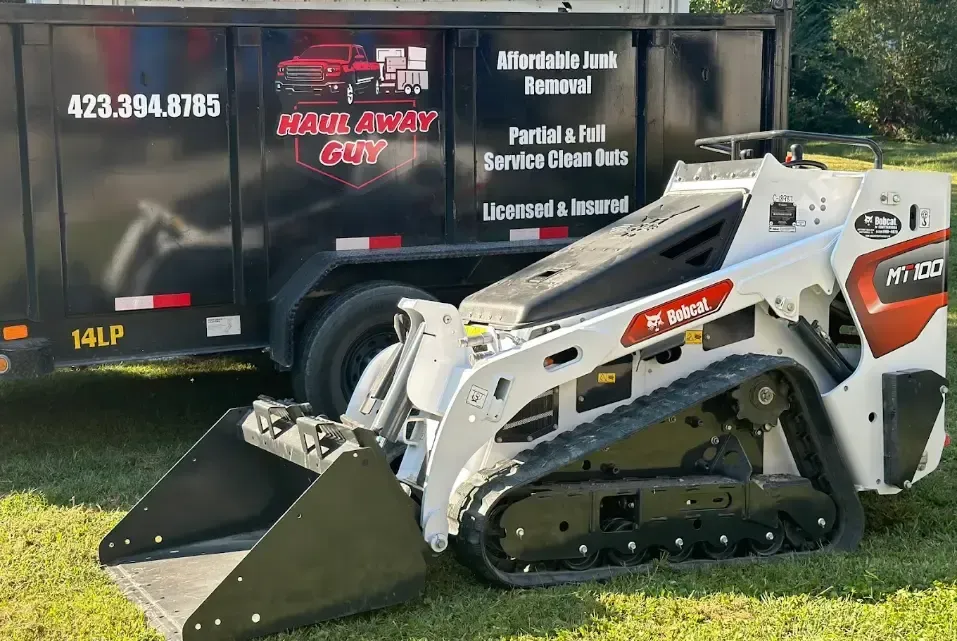 A bulldozer is parked in front of a dumpster.